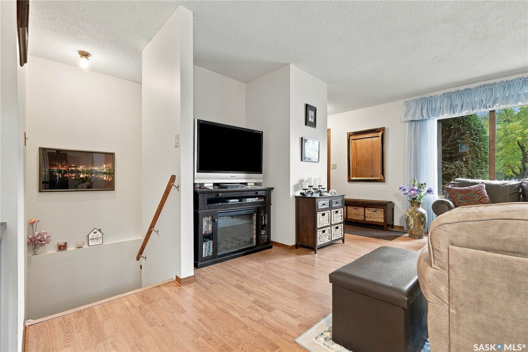 Wood-finish flooring, white painted walls, and a large window with ample natural light