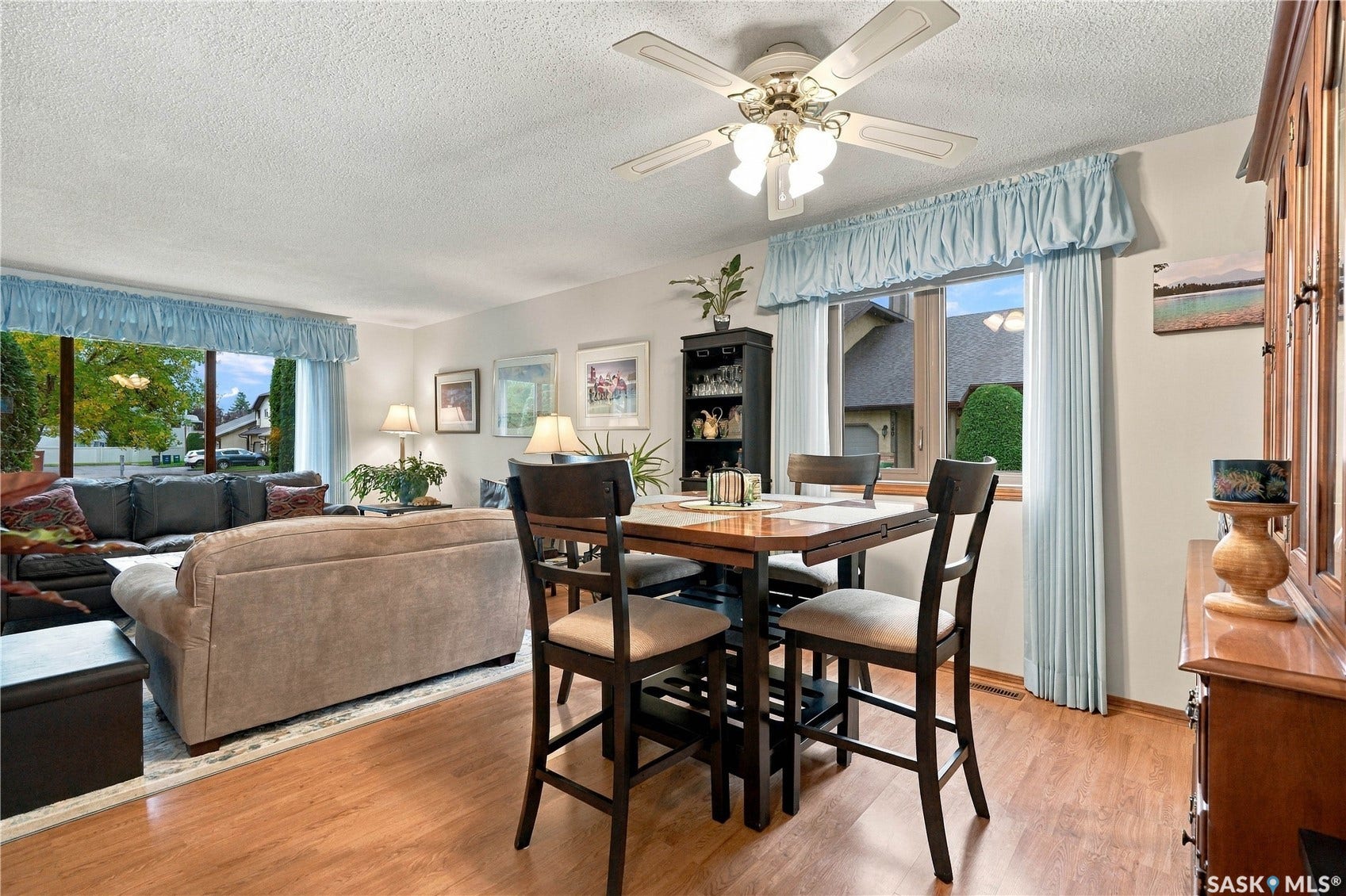 Wood-finish flooring throughout, with a ceiling fan featuring integrated lighting, and a large picture window