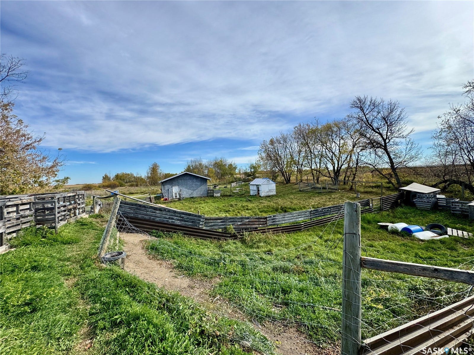 Expansive open area featuring a utility building, a smaller storage structure, and perimeter fencing
