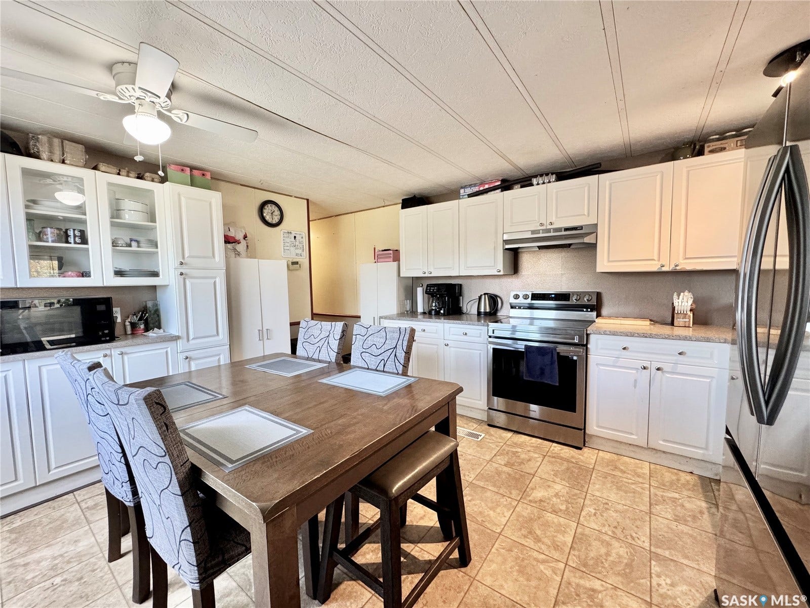 Kitchen featuring white cabinetry, tile flooring, stainless steel appliances, a ceiling fan, and a built-in dining table