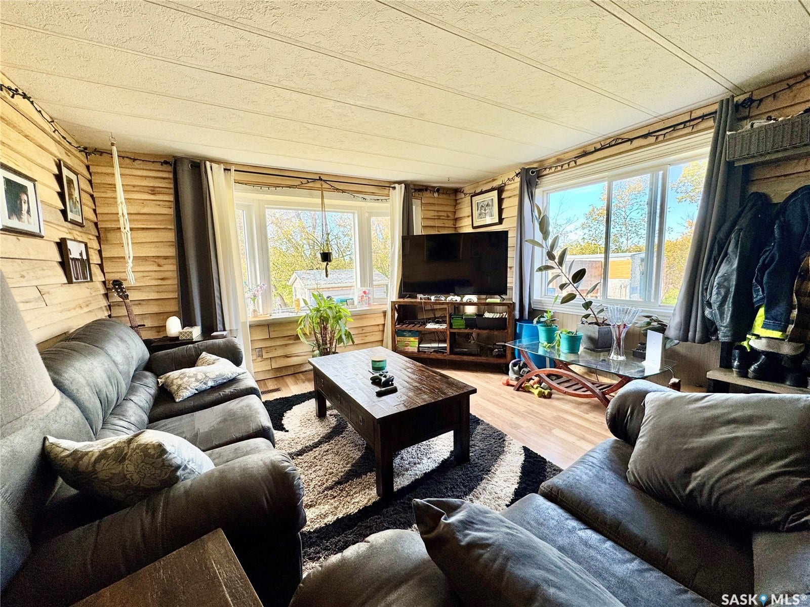 Wood-finish wall paneling, large windows, wood-finish flooring, and a drop ceiling with visible support beams