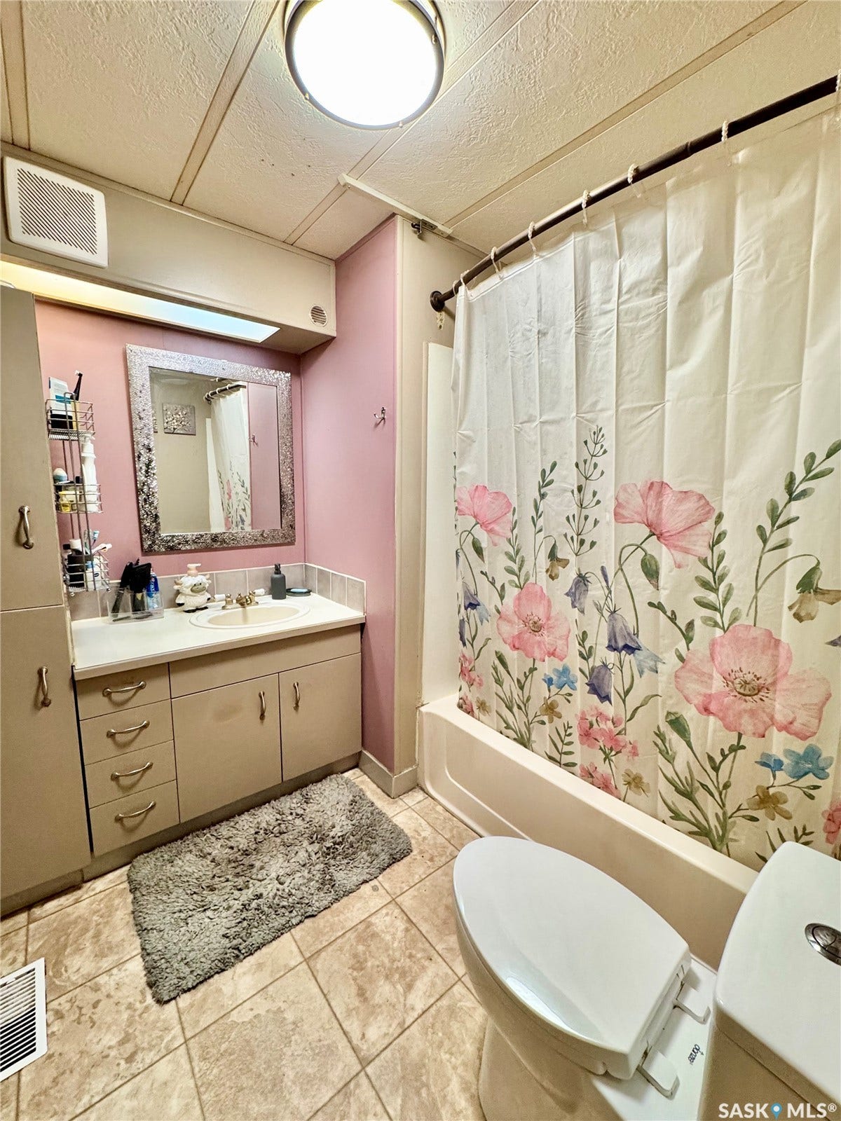 Bathroom featuring a built-in vanity with a countertop and integrated sink, cabinet storage, decorative wall mirror, and a full bathtub with shower