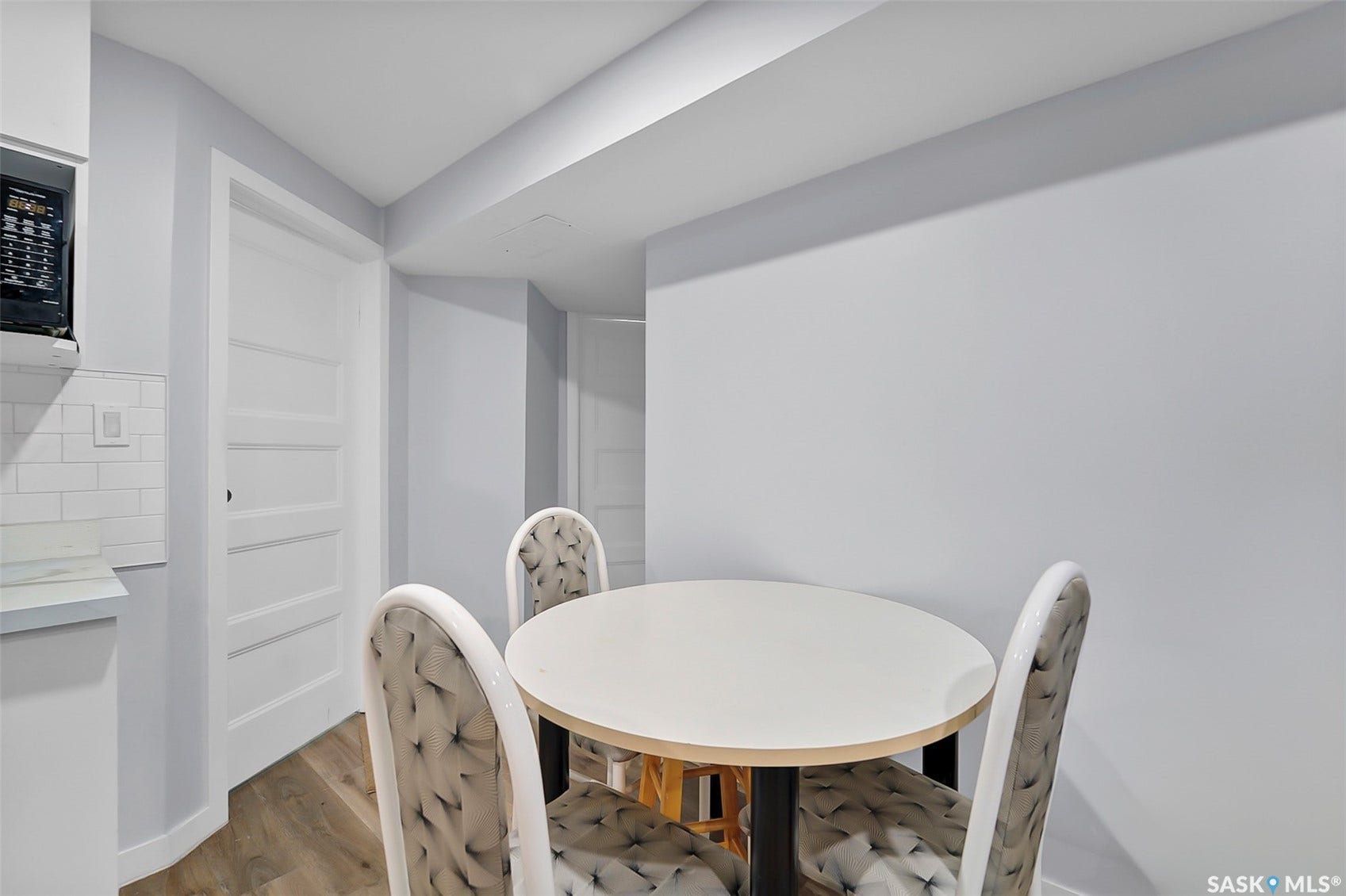 Wood-finish flooring with white baseboards, a white subway tile backsplash, and a white countertop