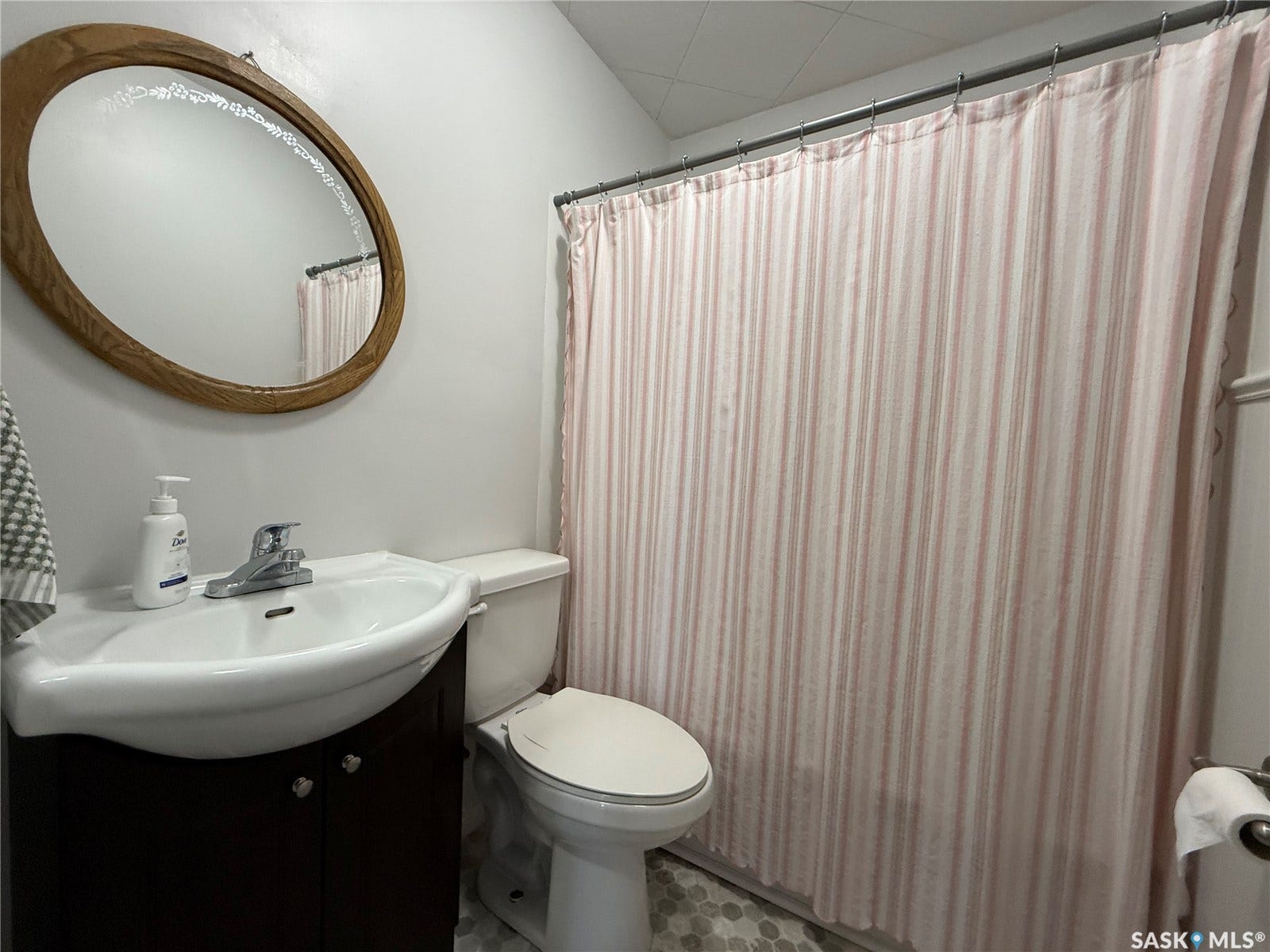 Pedestal sink with a dark wood-finish vanity, oval mirror, and tiled flooring