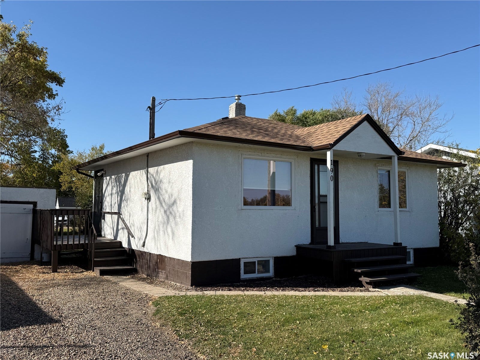 Stucco exterior with a brown shingle roof and covered entry porch