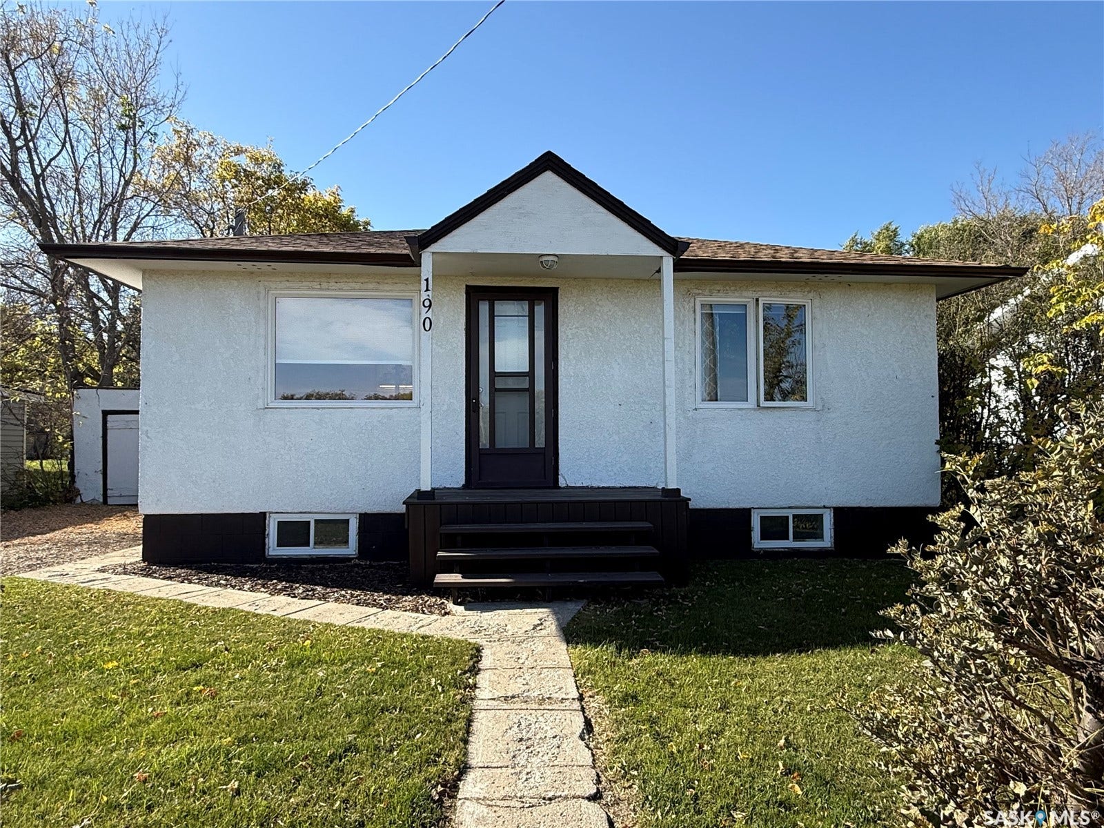 White stucco exterior with dark trim accents, featuring a prominent front porch with steps