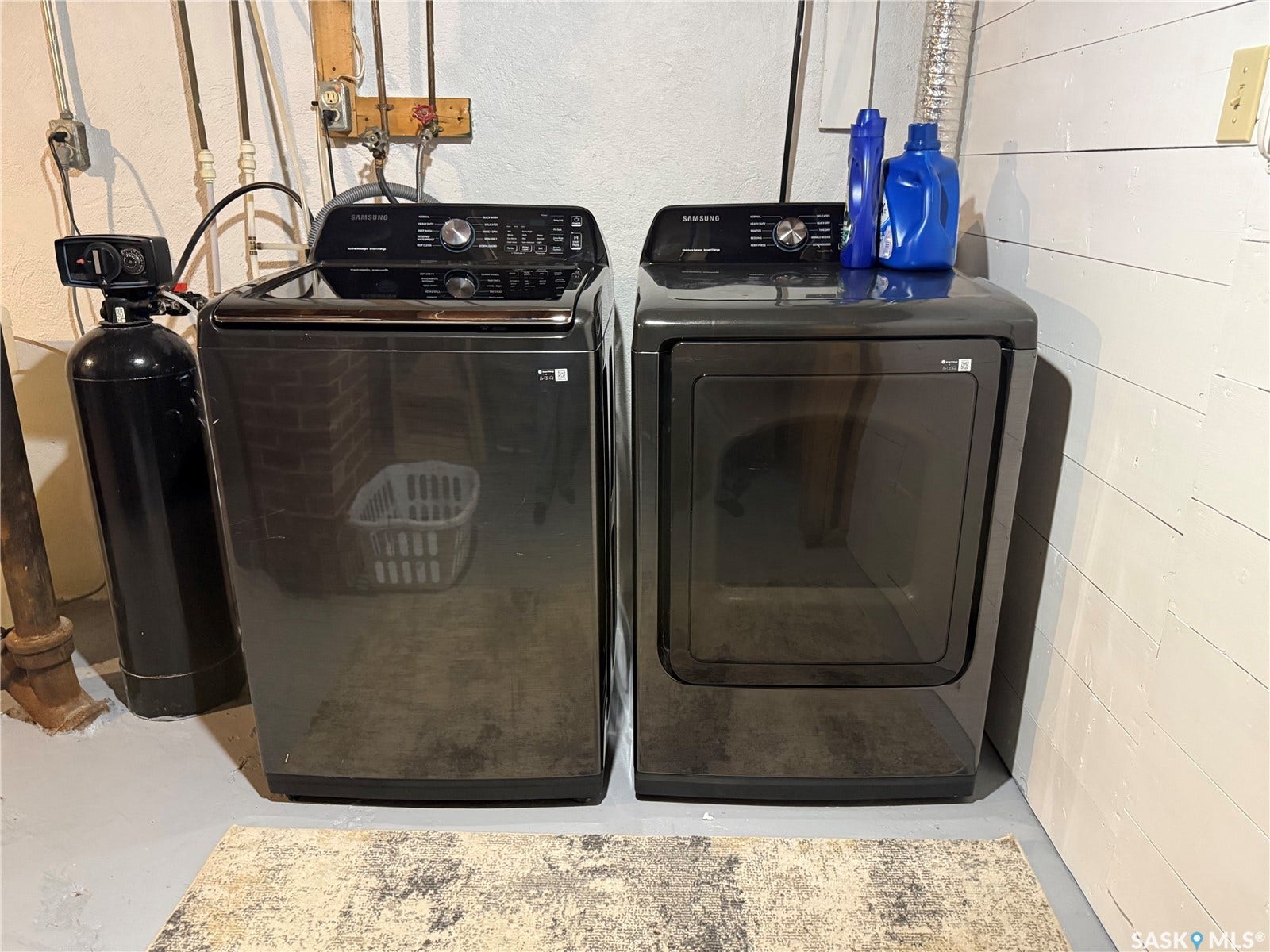 Laundry area with a washer and dryer set, featuring a dark finish and top-mounted controls
