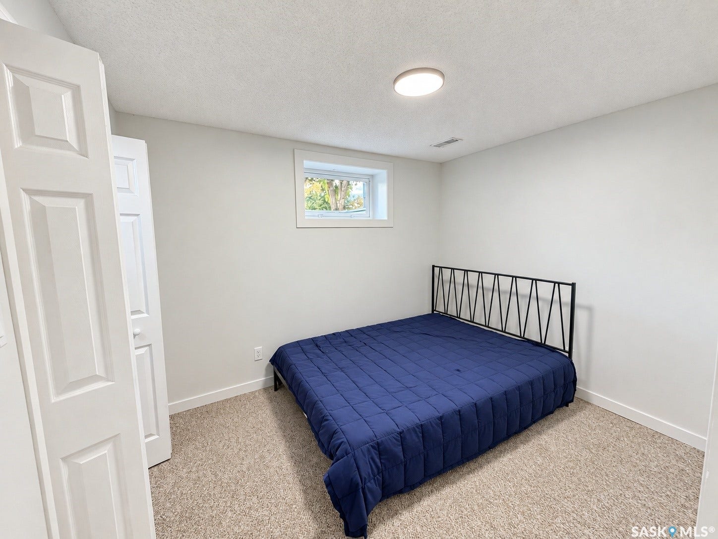 Carpeted room featuring a single window, white trim, and a flush-mount ceiling light