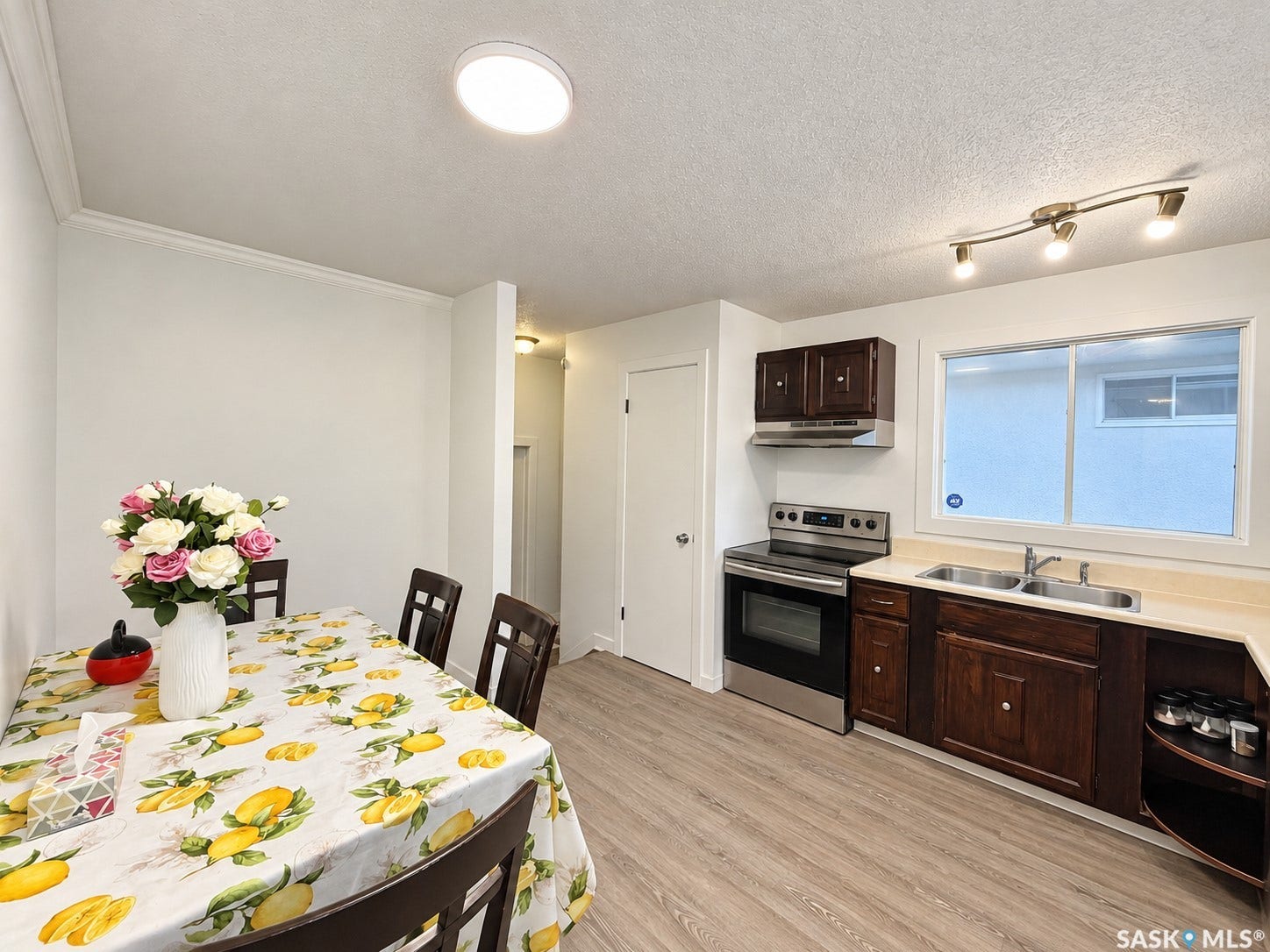 Kitchen with wood-finish flooring, stainless steel appliances, dark wood-finish cabinetry, and a double basin sink