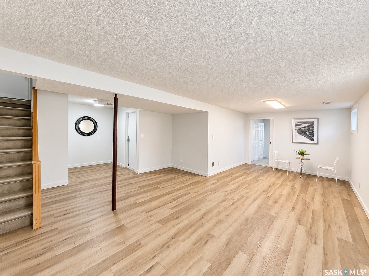 Spacious room with wood-finish flooring, light neutral wall tones, and recessed lighting