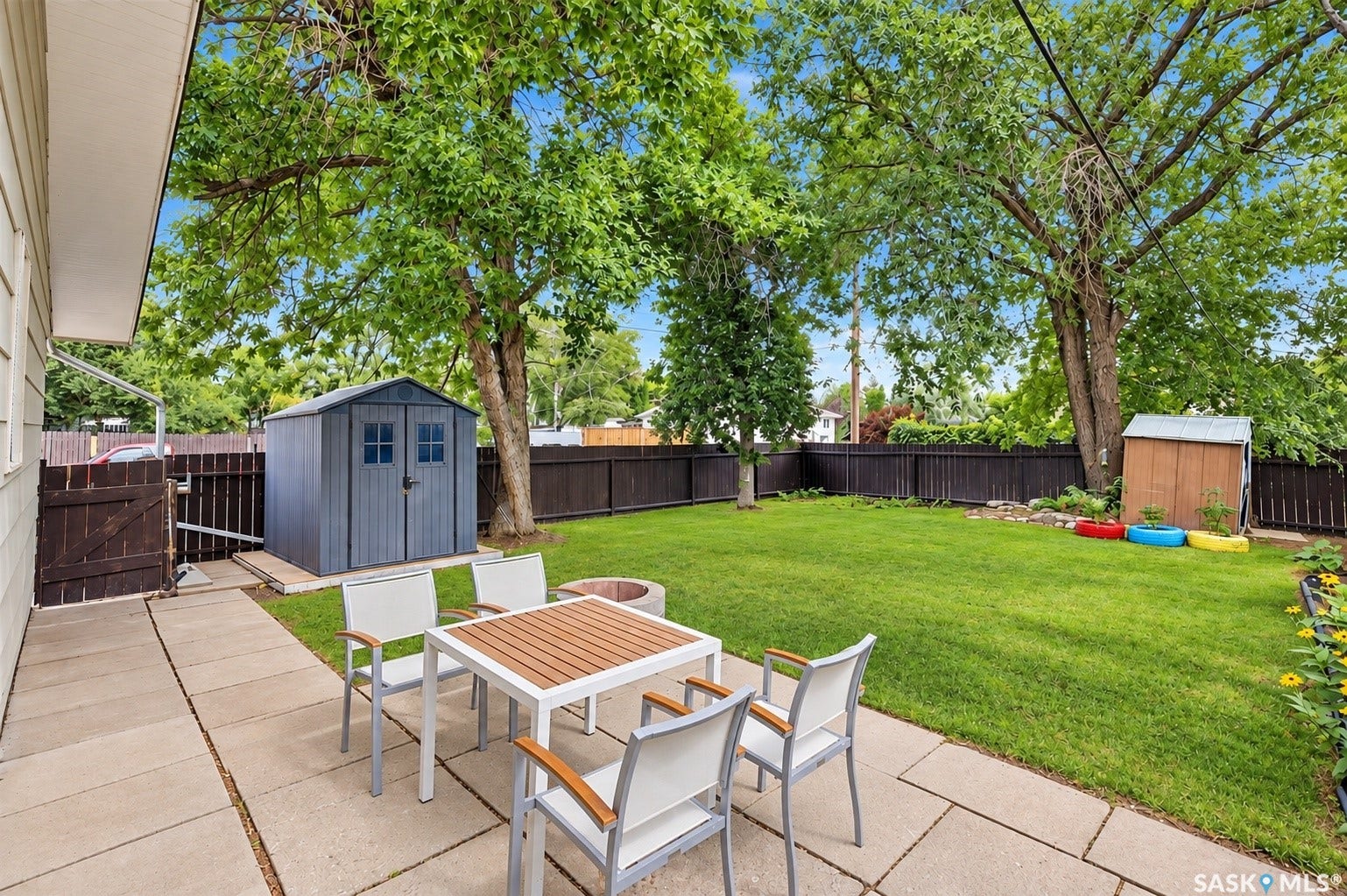 Expansive backyard featuring a manicured lawn, established trees, and a concrete paver patio