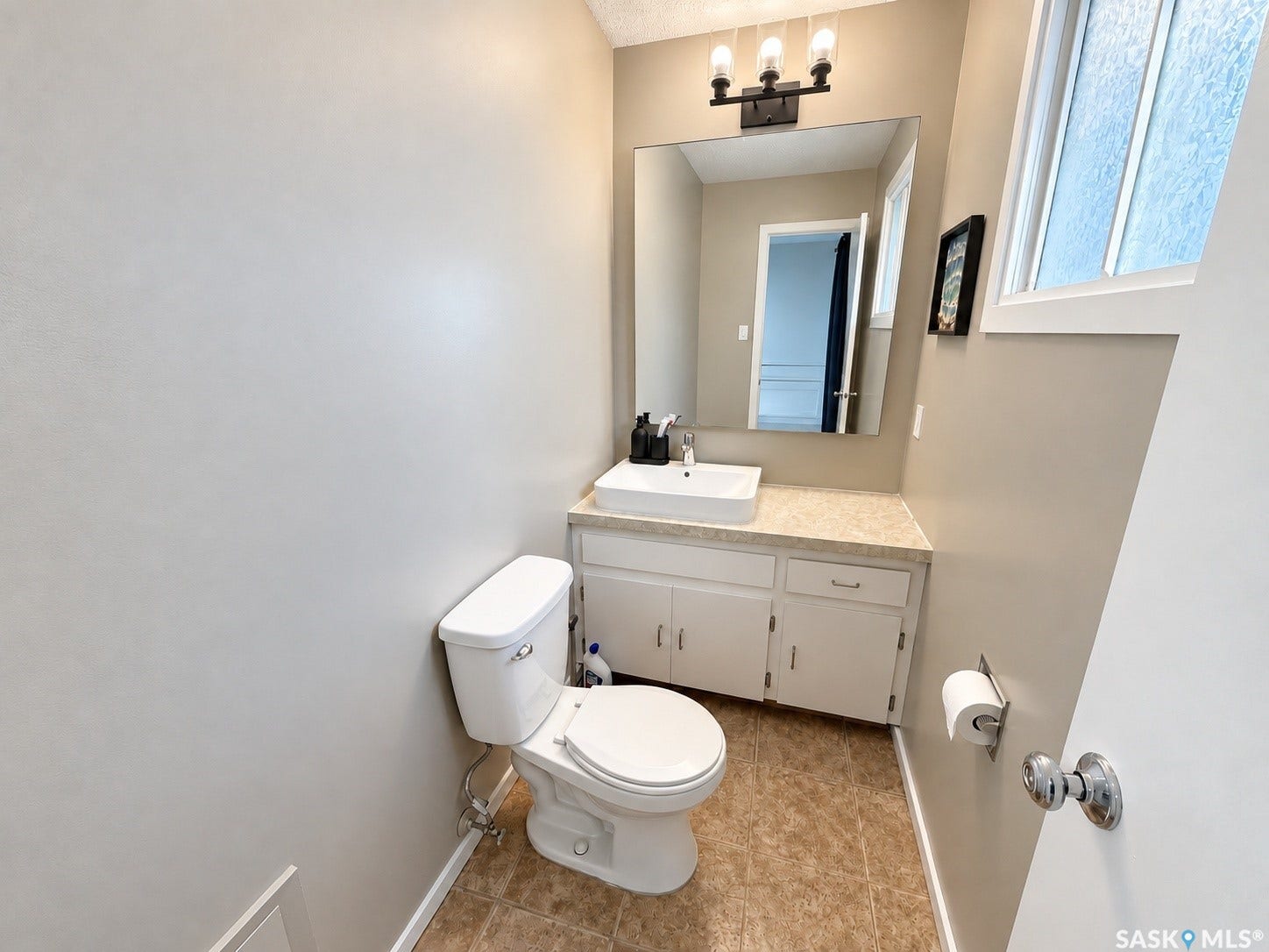 Vanity with a rectangular vessel sink, wall-mounted mirror, and overhead black-finish light fixture