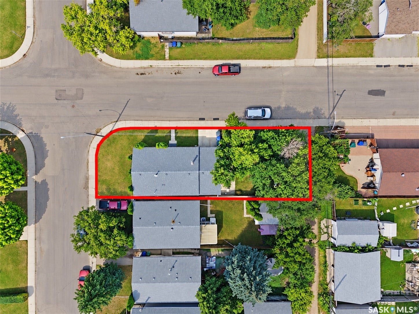 Corner lot property featuring a gray shingle roof and mature trees