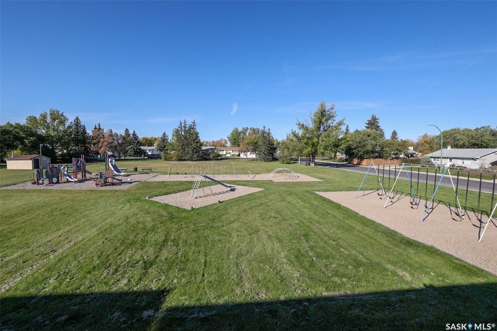 Expansive green space featuring playground equipment, swings, and a climbing structure