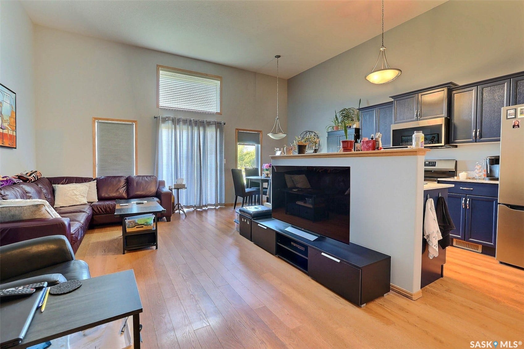 Vaulted ceilings, wood-finish flooring, sliding glass door, and dark-toned cabinetry with stainless appliances