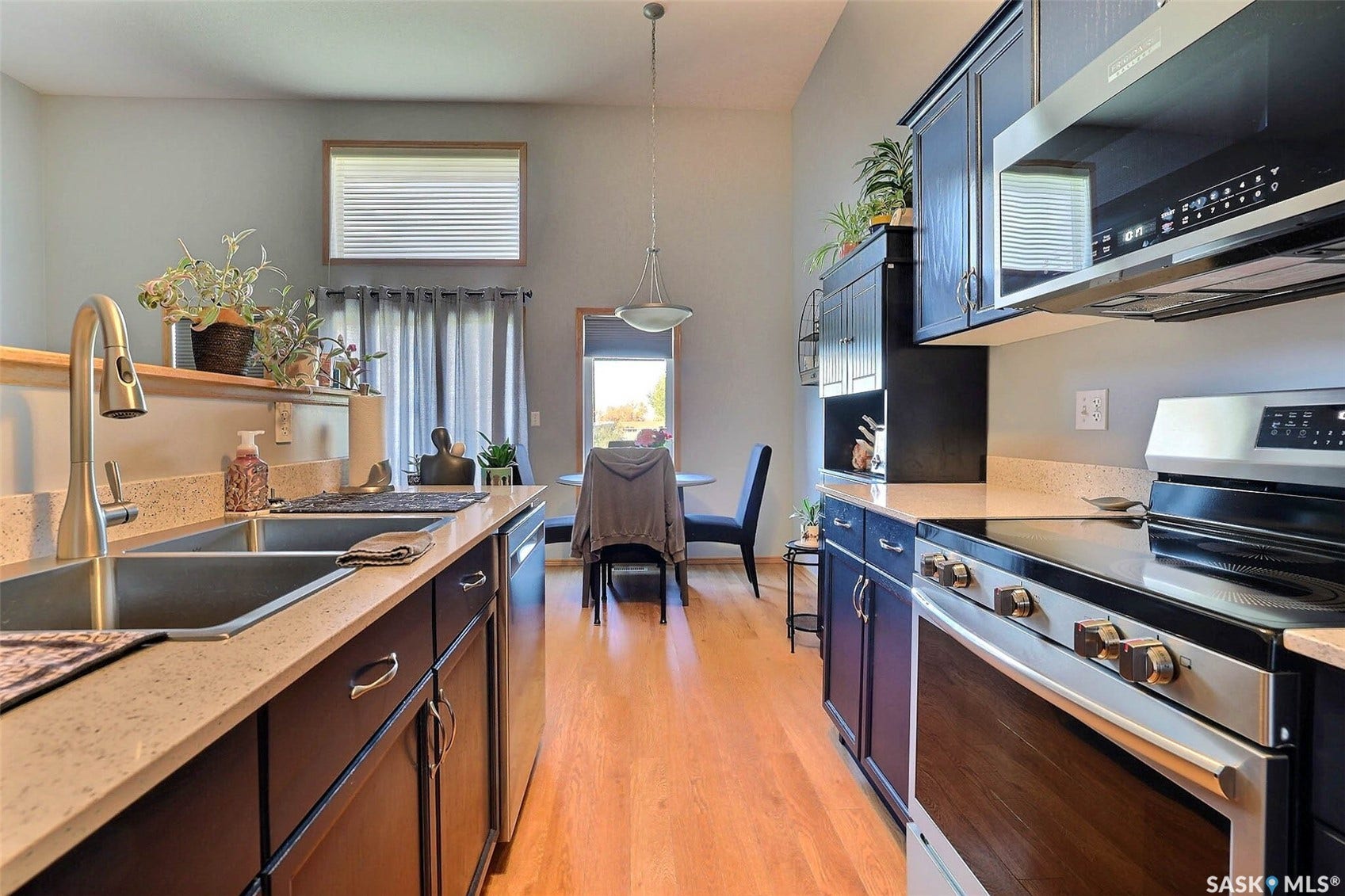 Kitchen featuring wood-finish flooring, dark wood cabinetry, light-toned countertops, and stainless steel appliances