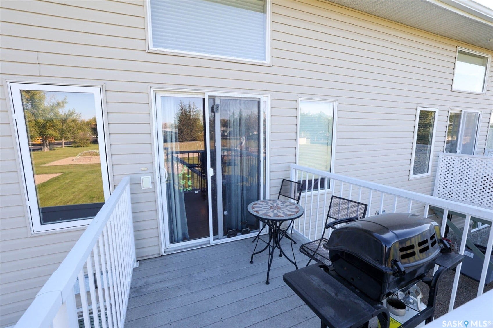 Deck with white railing, sliding glass door, and vinyl siding
