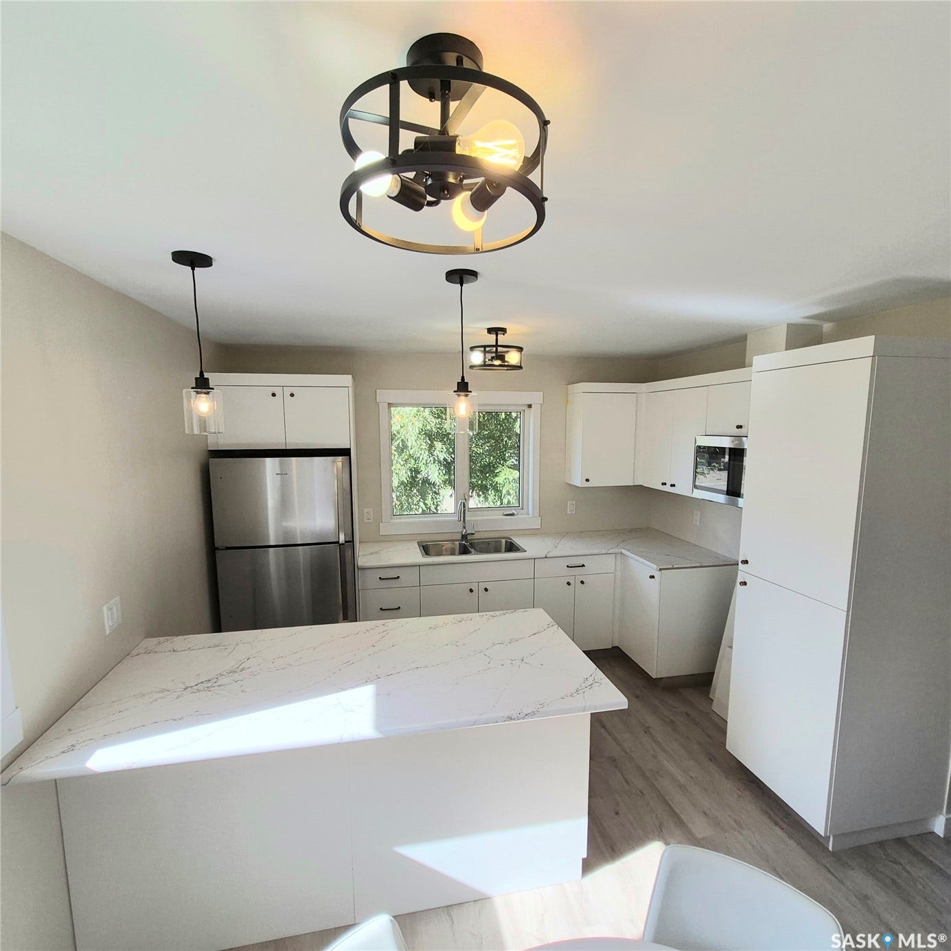 Modern kitchen featuring white cabinetry, stainless steel appliances, quartz countertops, a kitchen island, and contemporary light fixtures