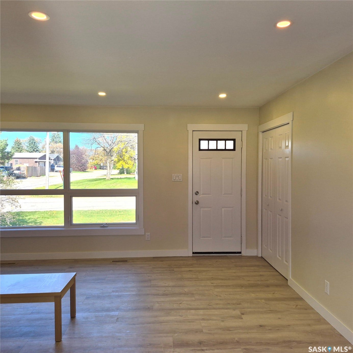 Recessed ceiling lighting, wood-finish flooring, white trim accents, multi-pane front door, and a built-in bi-fold closet