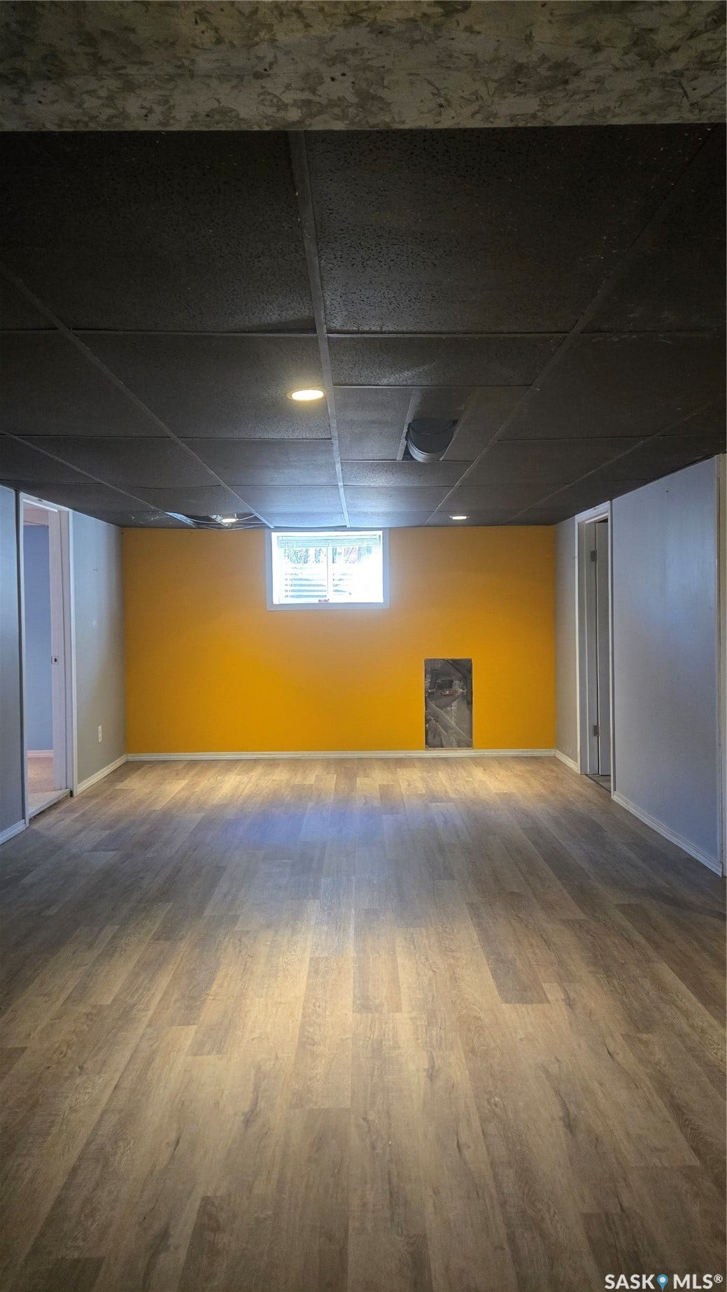 Recessed lighting with a suspended ceiling, wood-finish flooring, and a window with blinds