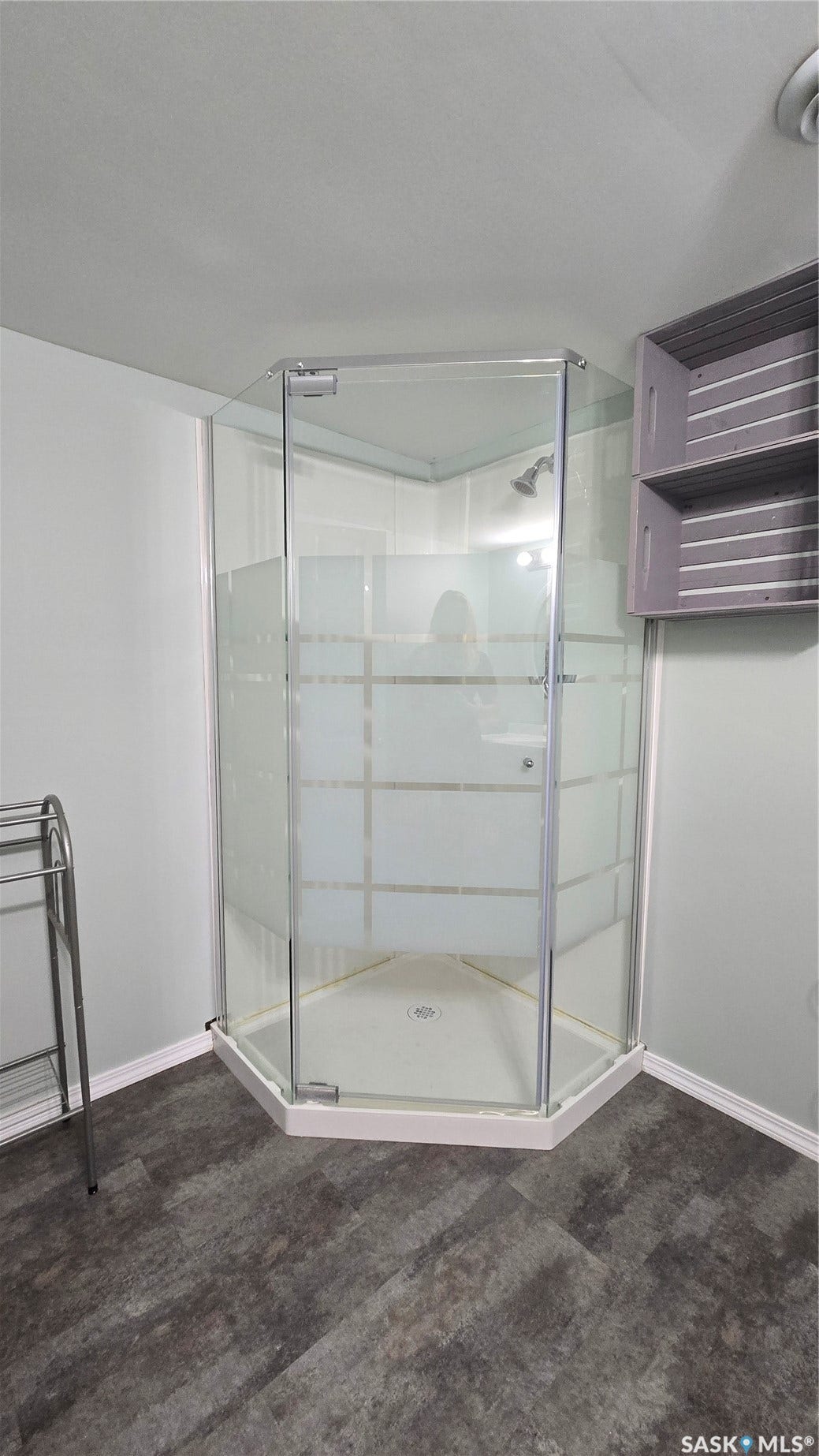 Corner shower enclosure with clear glass panels, white base, and a chrome shower head