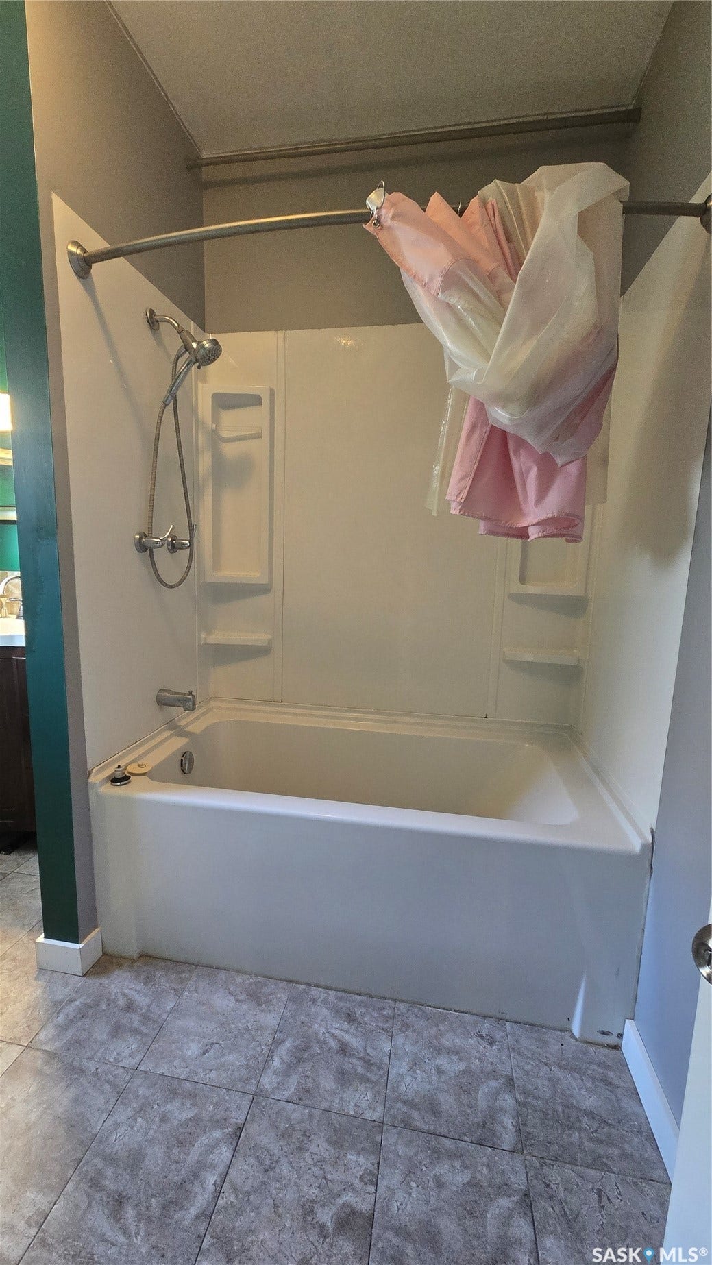 Bathtub with an integrated shower, white shower surround with built-in shelving, and a curved shower rod