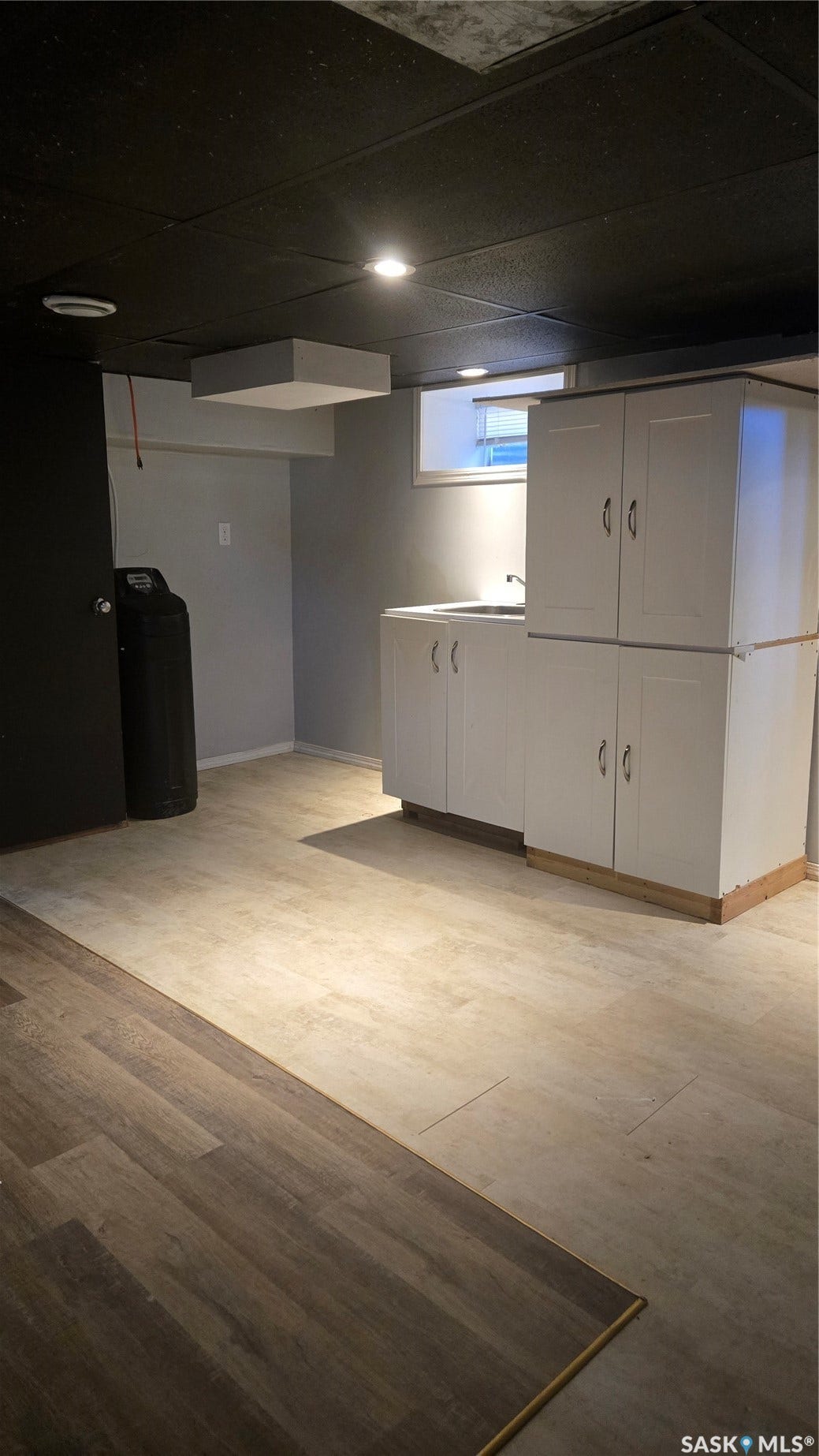 White cabinetry with a countertop sink, recessed ceiling lighting, and wood-finish flooring