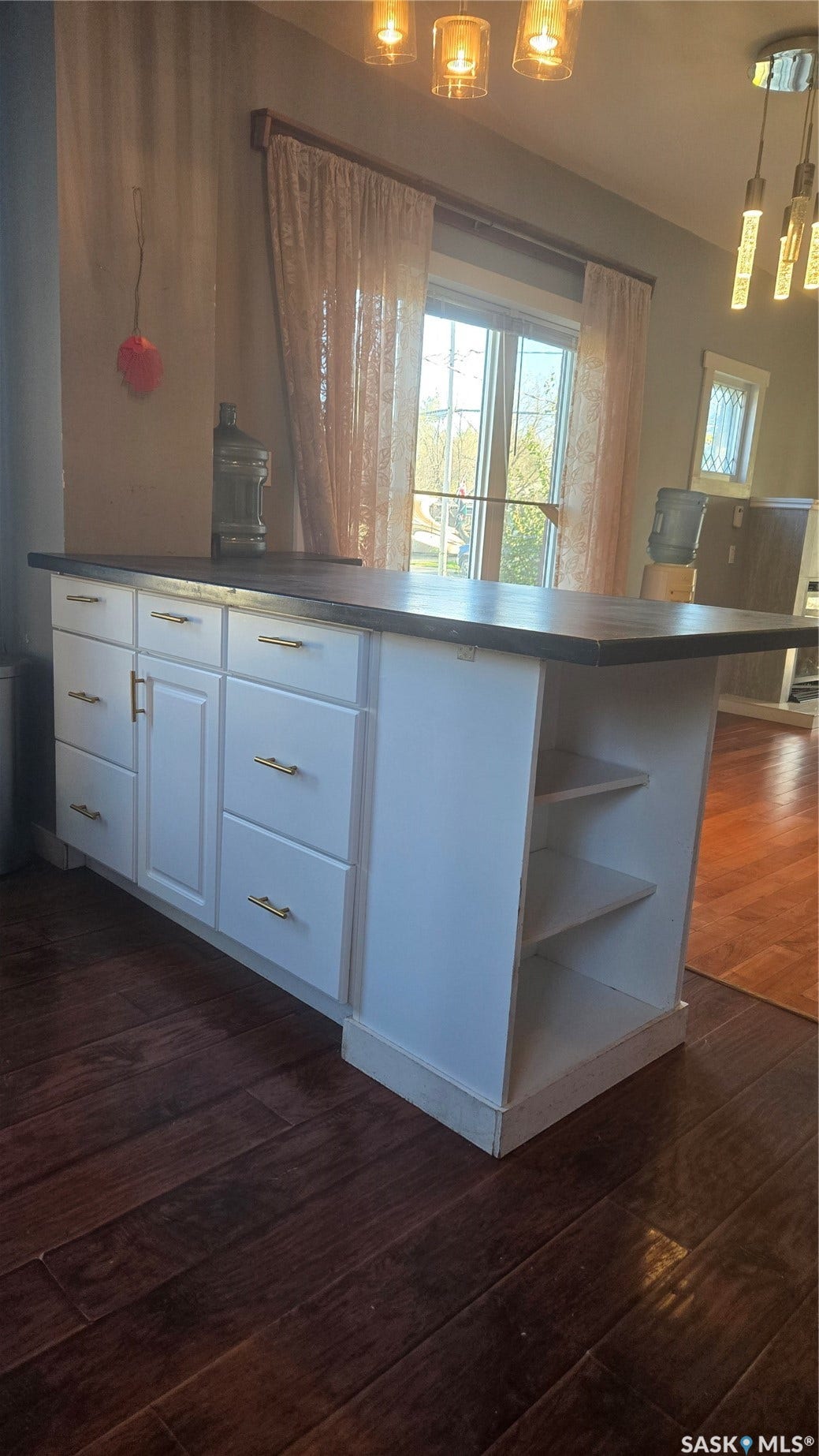 Kitchen island with white cabinetry, gold-finish hardware, and built-in shelving