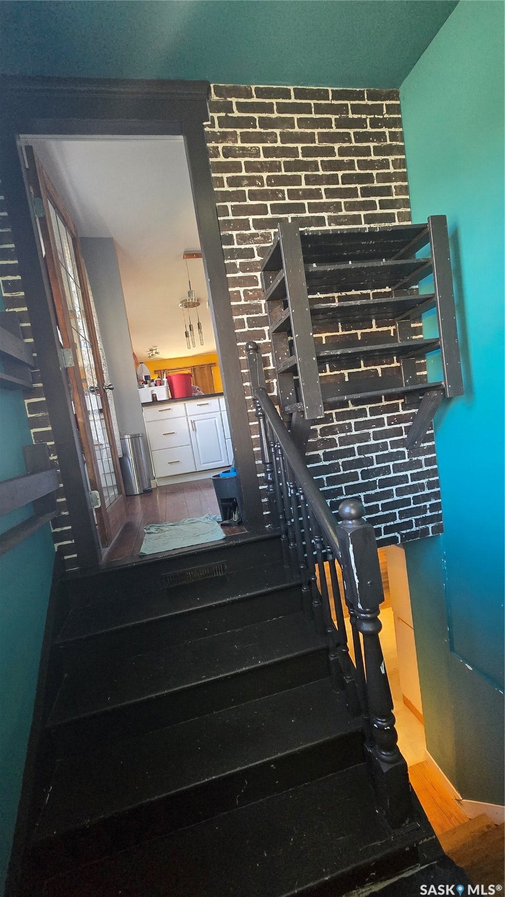 Black painted staircase with a matching handrail and balusters, accompanied by a black and white brick-patterned accent wall