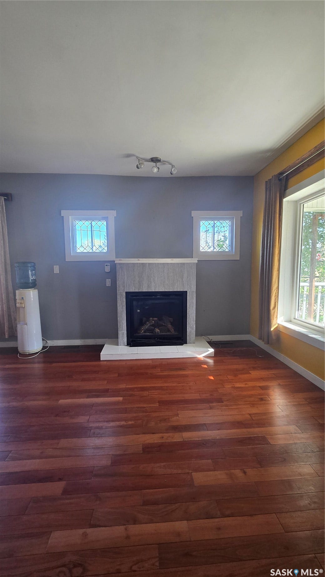 Hardwood flooring, tiled fireplace with hearth, and decorative transom windows