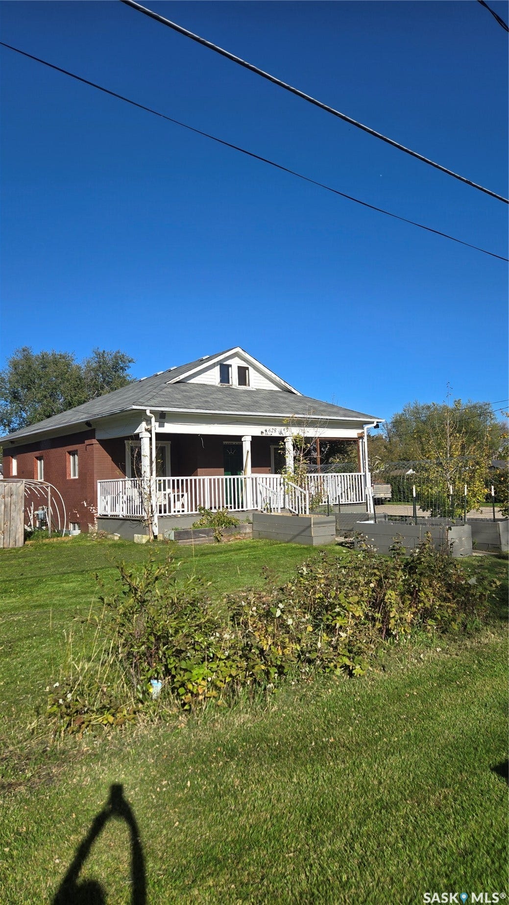 Brick exterior with a covered front porch featuring white railings and columns, and a gabled roofline with attic windows