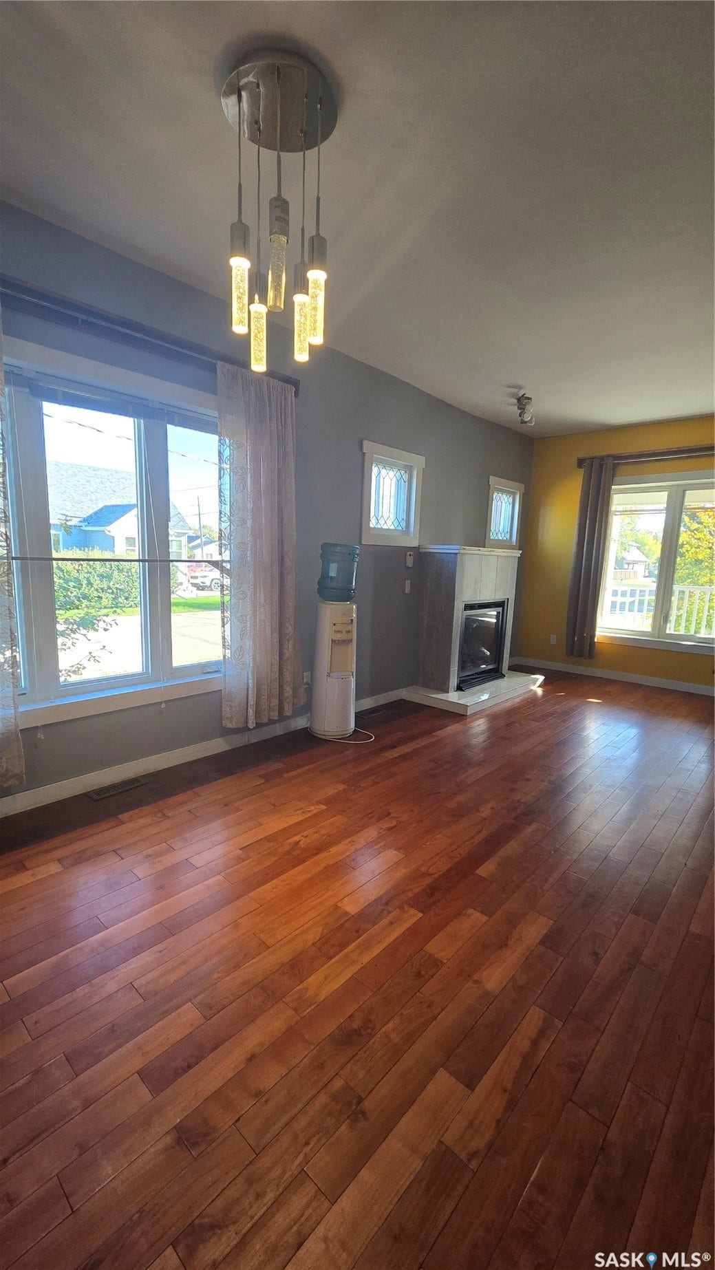 Wood-finish flooring throughout, modern hanging light fixture, large windows, recessed lighting, and a built-in fireplace