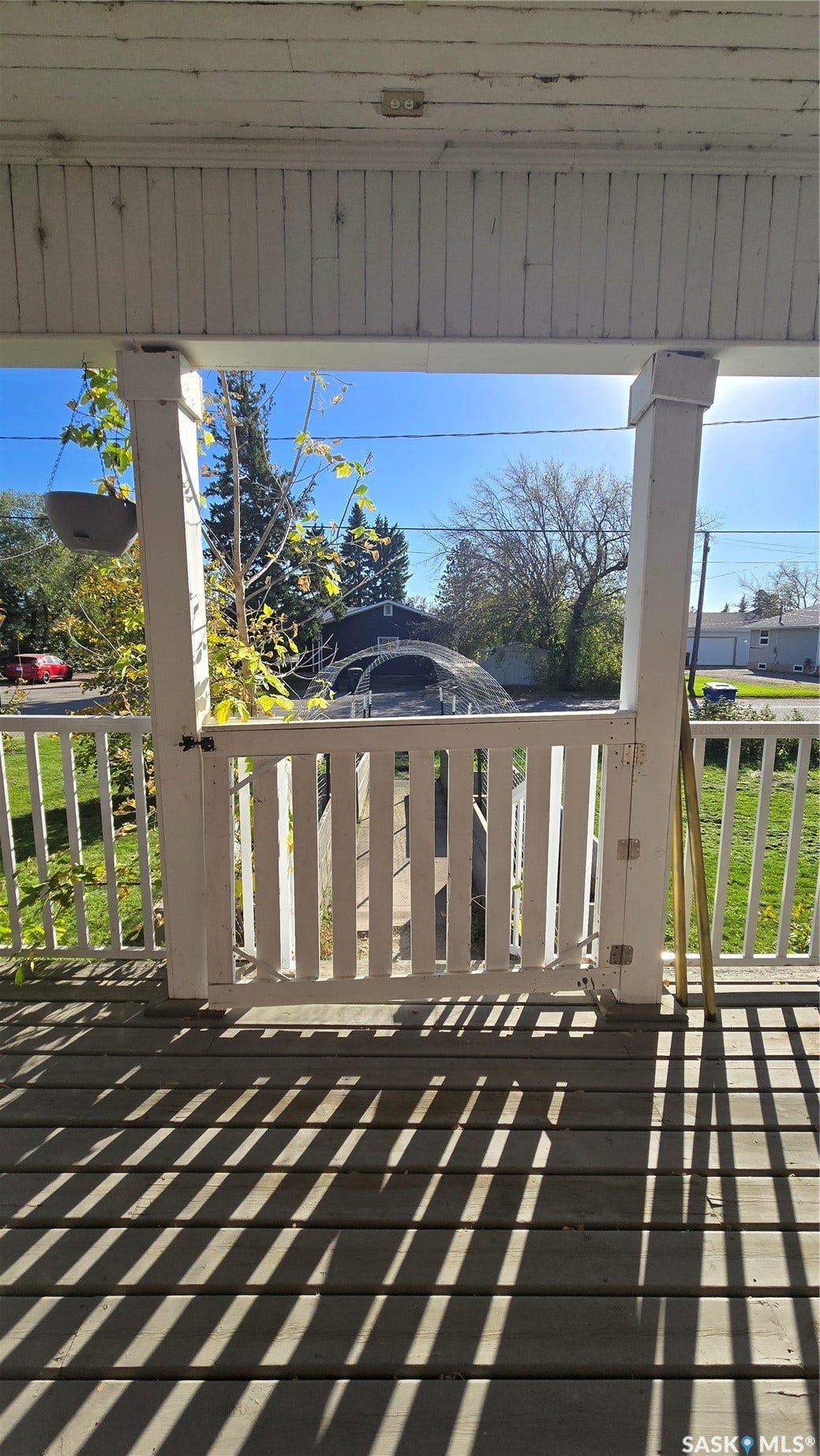 Porch featuring a slatted wood deck, painted railings, and a white picket gate