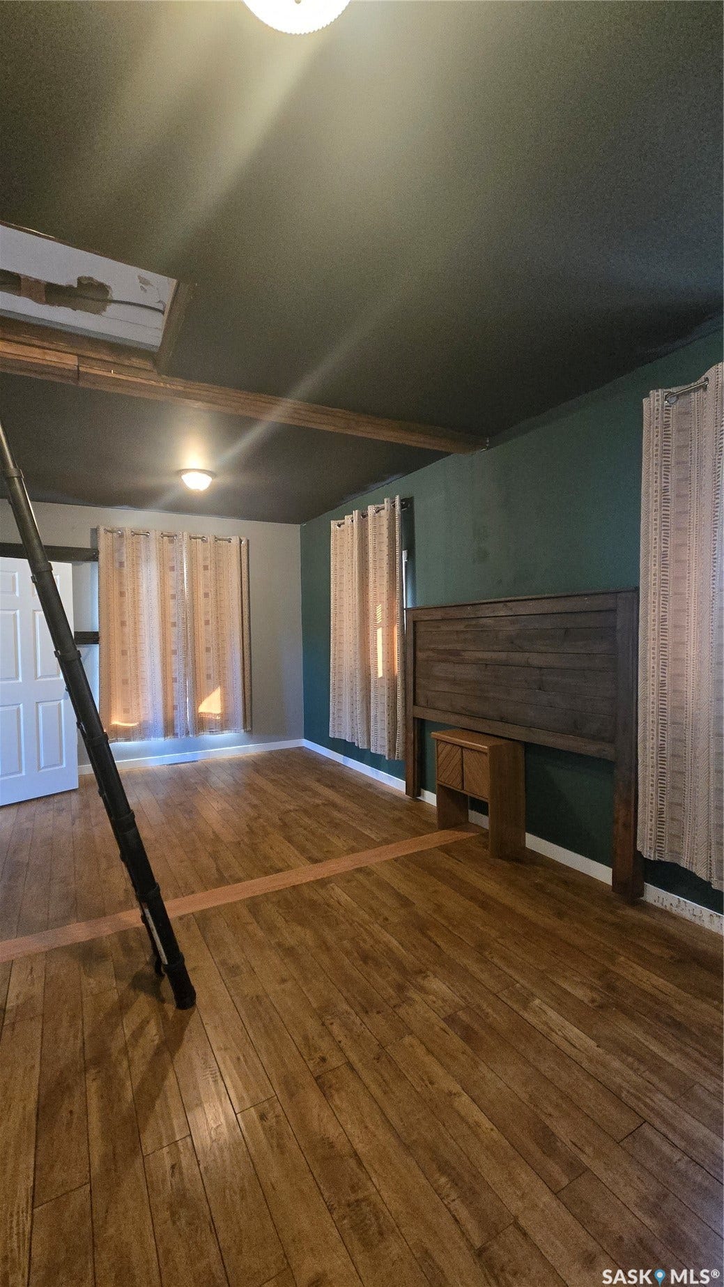 Wood-finish flooring with a contrasting accent strip, exposed ceiling beams, and recessed lighting