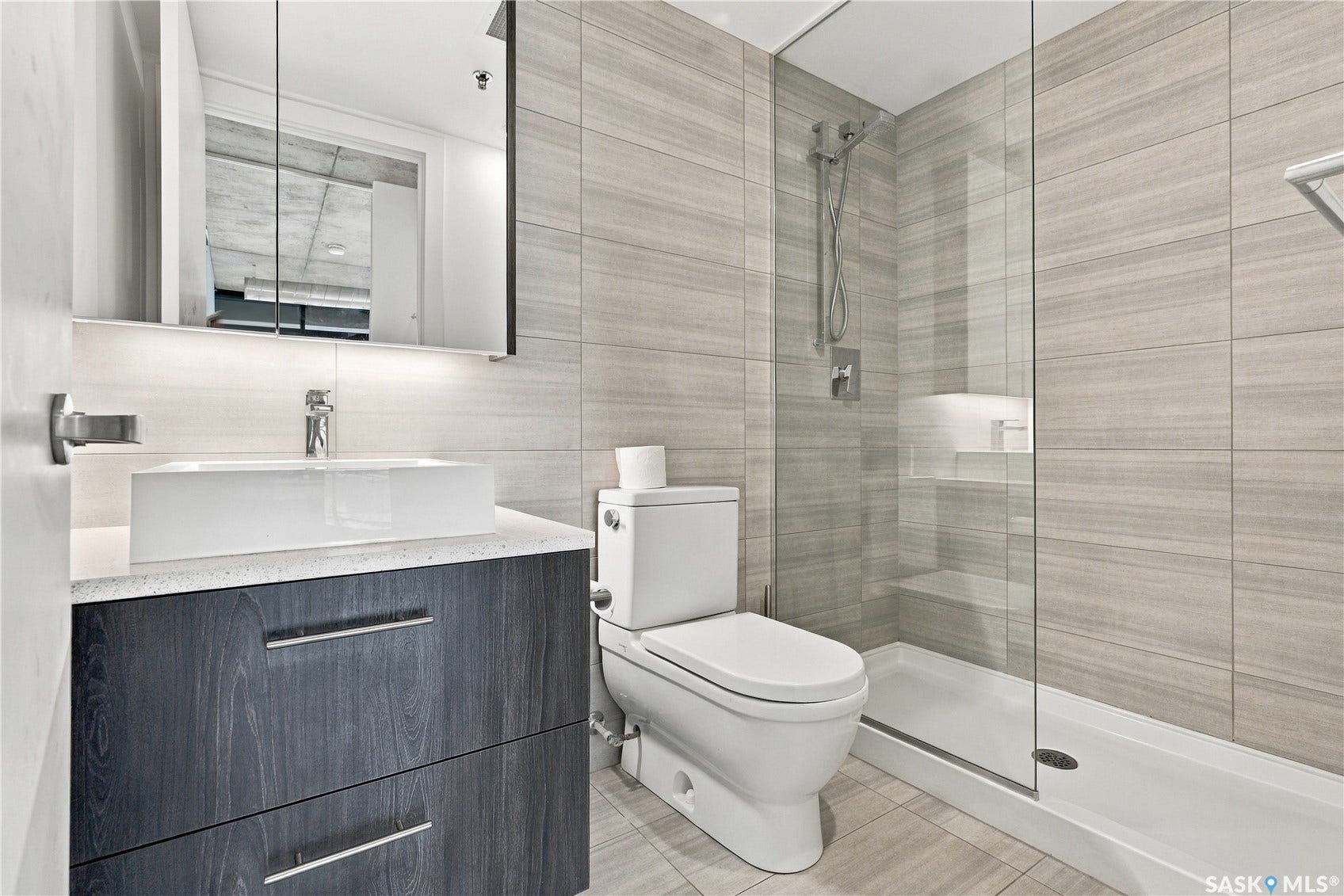 Vanity with a vessel sink, dark wood-finish cabinetry, and a light countertop
