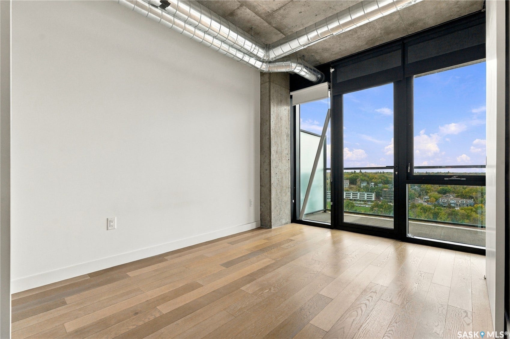 Light wood-finish flooring with a concrete ceiling and exposed ductwork