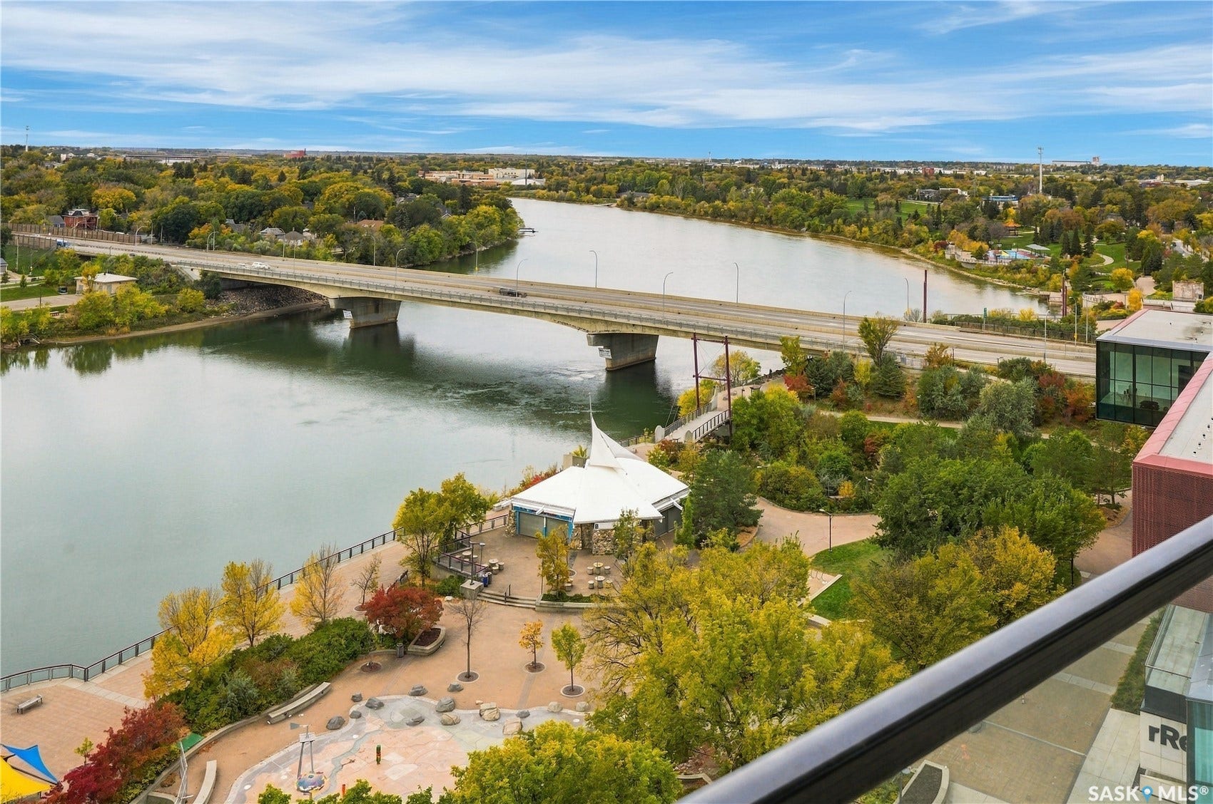 Expansive riverfront setting featuring a modern bridge, extensive parkland, and a prominent waterfront structure