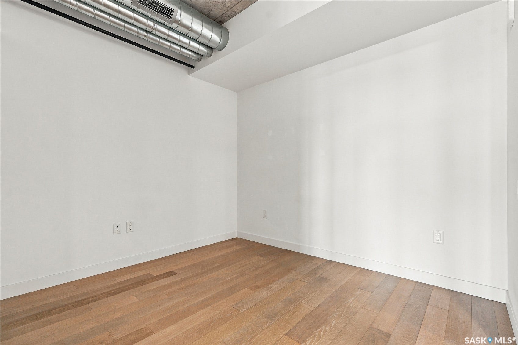 Wood-finish flooring with white walls and exposed ceiling ductwork