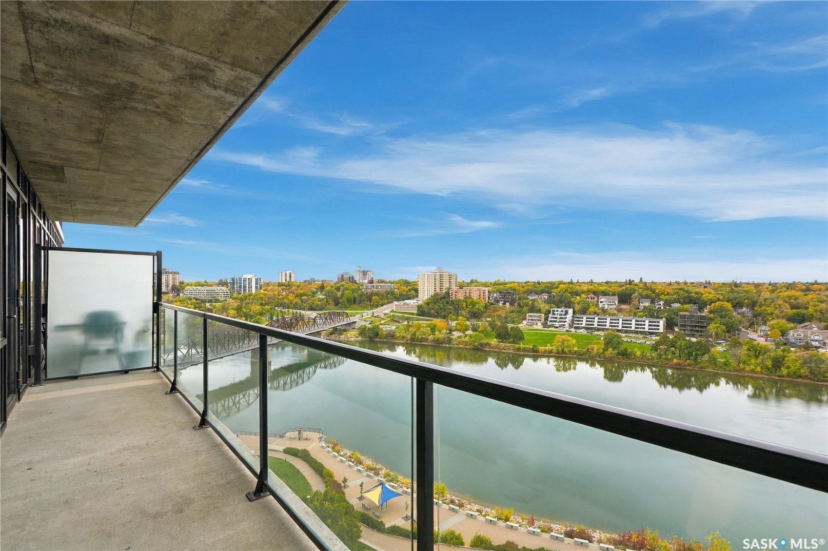 Spacious balcony featuring a concrete floor, glass and metal railing, and a partial privacy screen