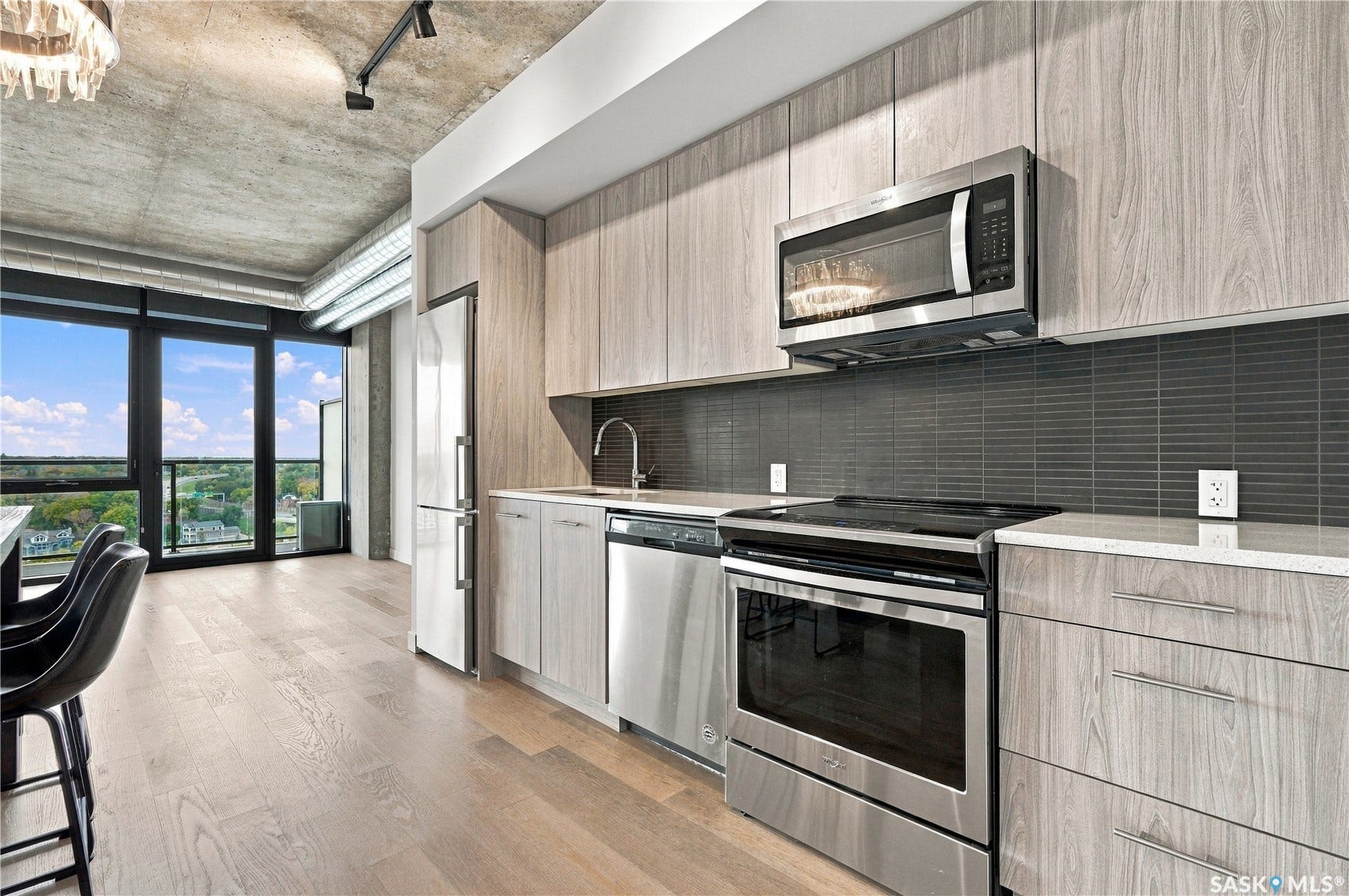 Contemporary kitchen featuring stainless steel appliances, wood-finish cabinetry, and light-tone flooring
