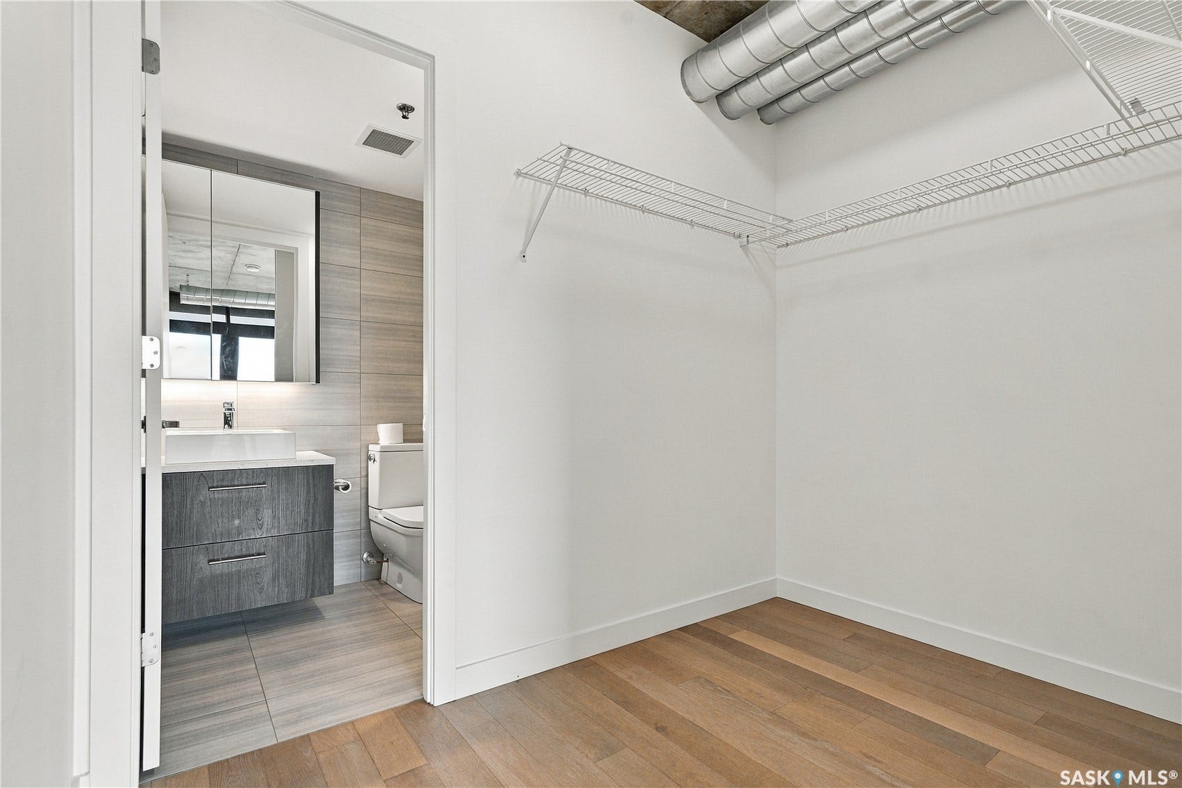Hardwood-style flooring with white walls and exposed ductwork