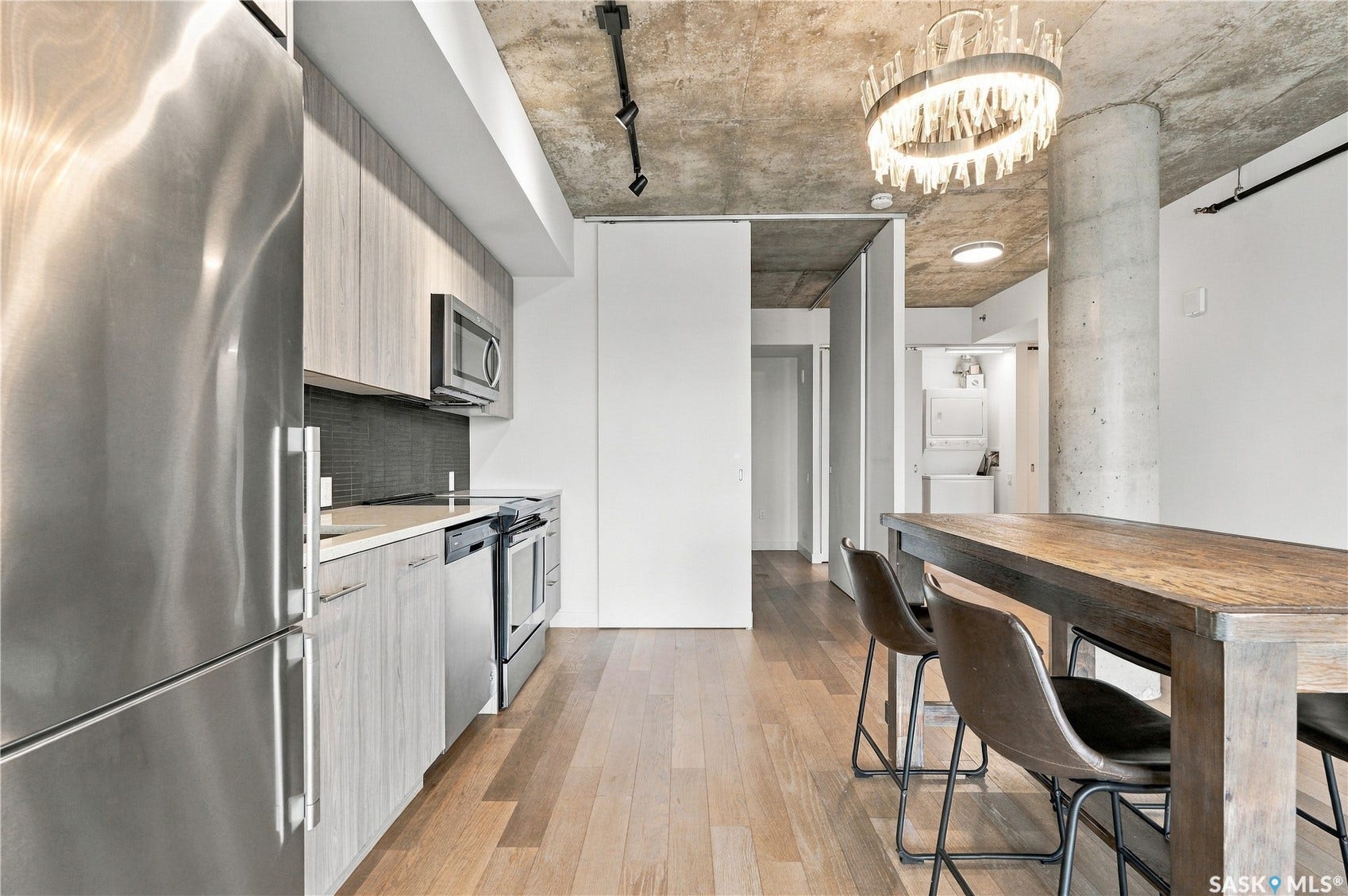 Kitchen featuring stainless steel appliances, wood-finish flooring, a concrete ceiling, and track lighting