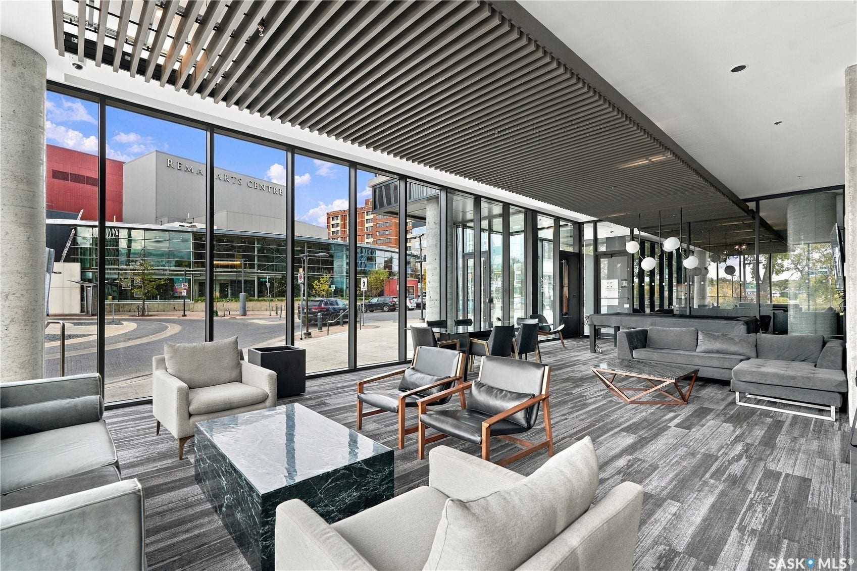 Expansive floor-to-ceiling windows, modern suspended ceiling paneling, durable gray-toned carpet, concrete support columns, and contemporary track lighting