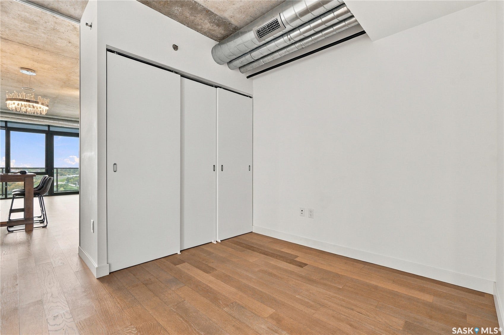 Hardwood flooring, concrete ceiling, exposed ductwork, and built-in closet storage
