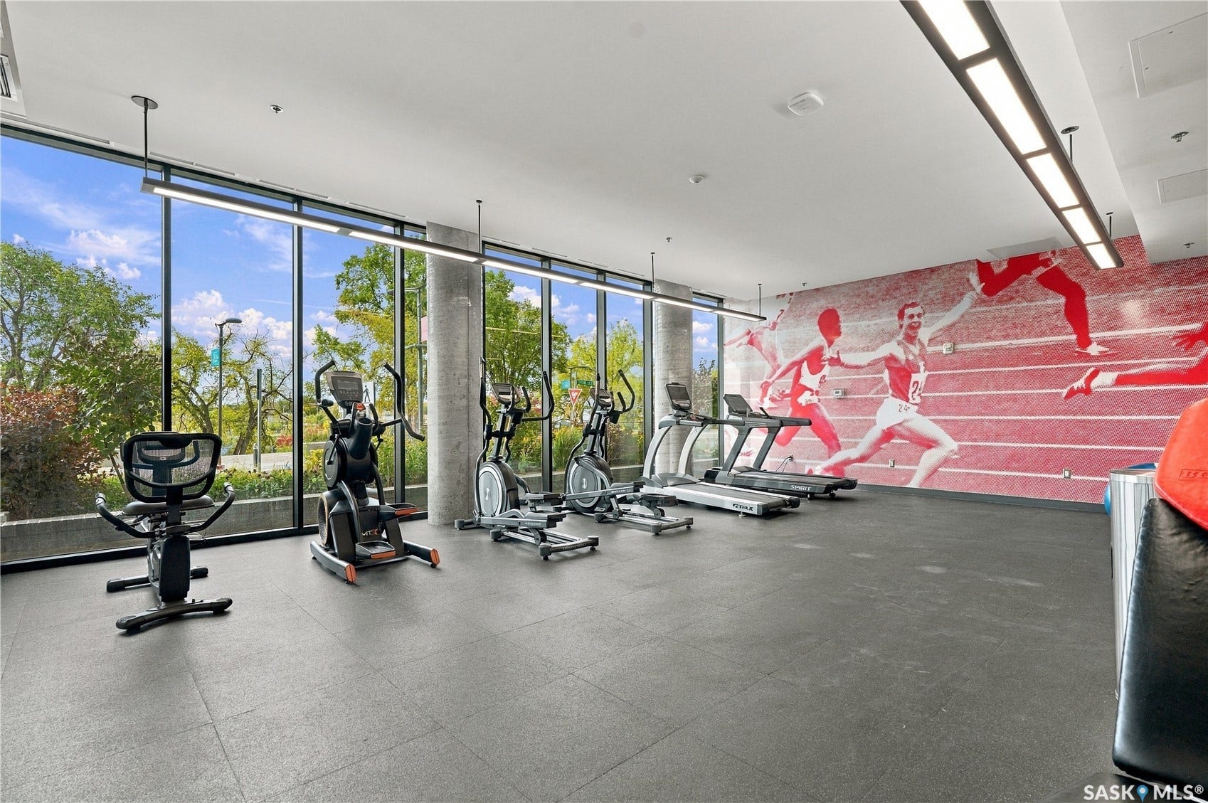 Full-height windows, concrete structural columns, resilient flooring, and integrated ceiling lighting