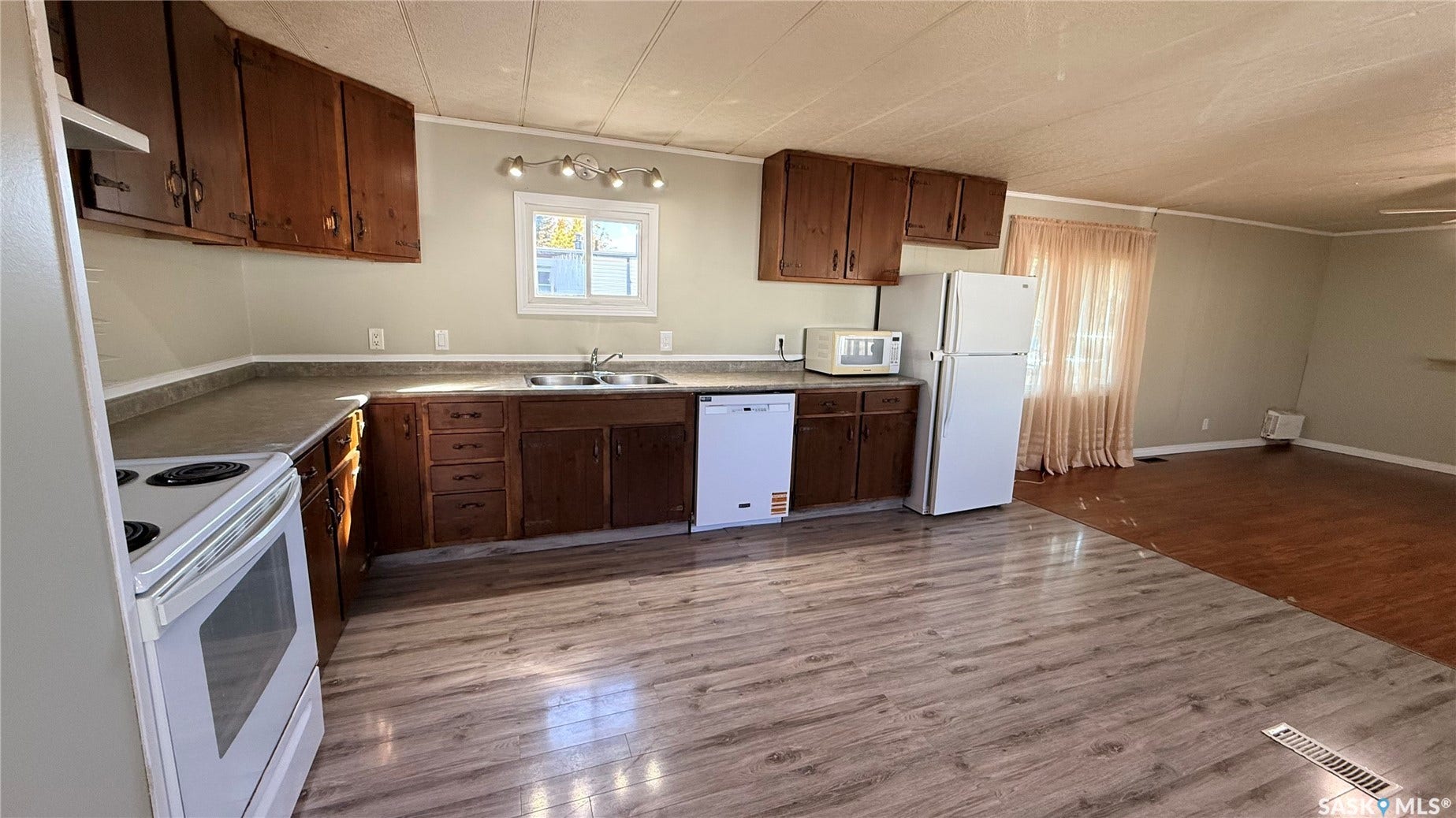 Kitchen featuring wood-finish cabinetry, white appliances, laminate countertops, and a window above the sink