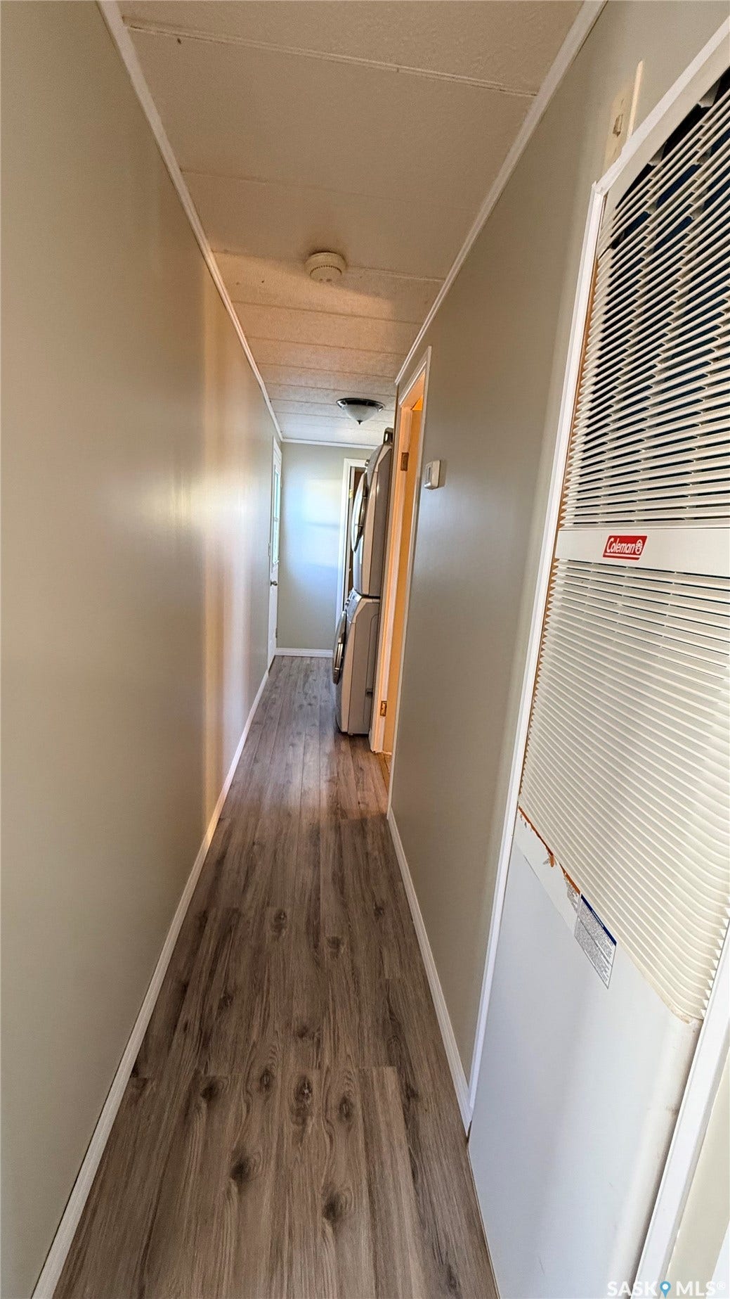 Wood-finish flooring throughout, light neutral wall paint, and a wall-mounted heating/cooling unit