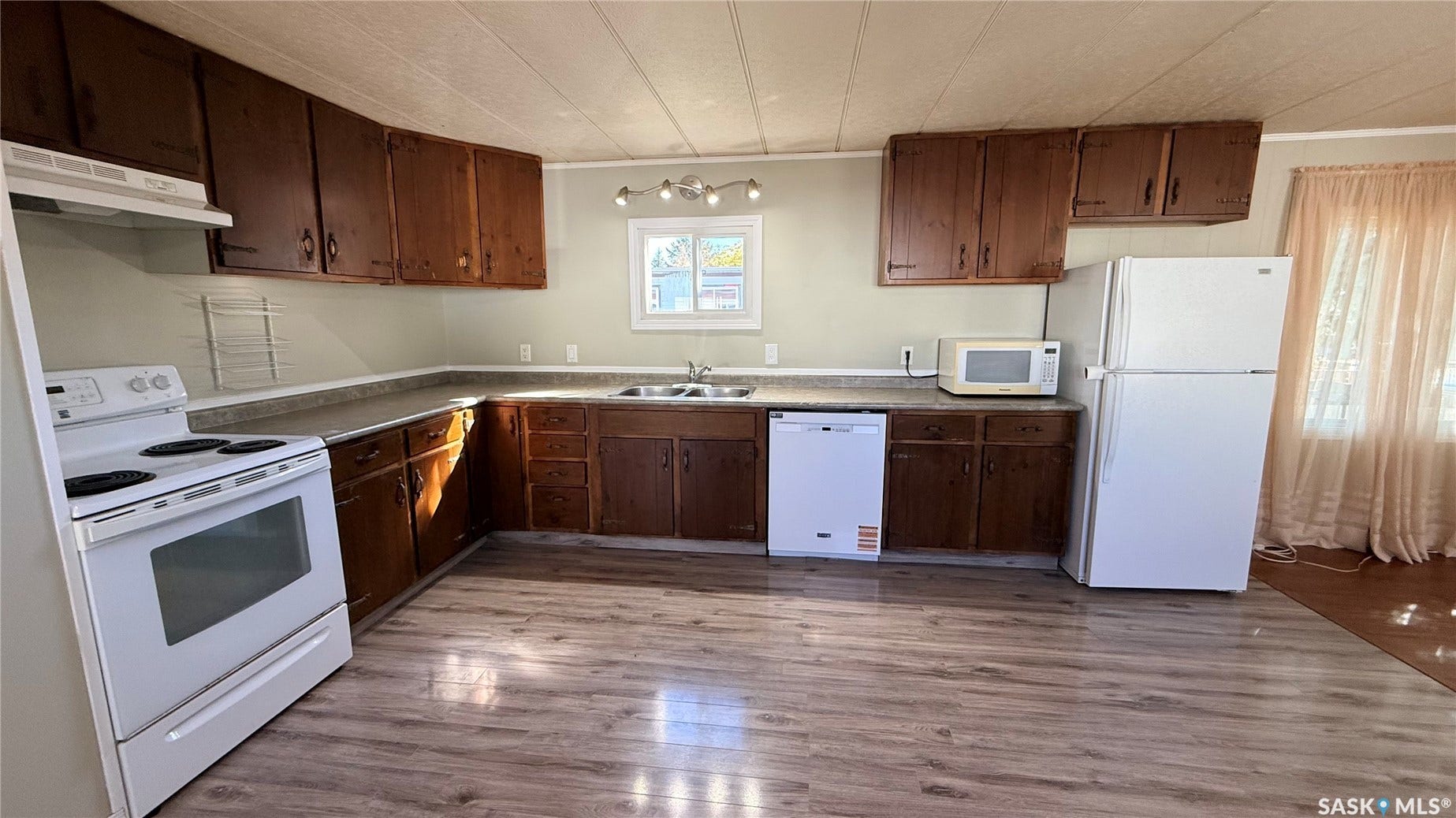Wood-finish flooring with a U-shaped countertop, wood cabinetry, and a double basin sink