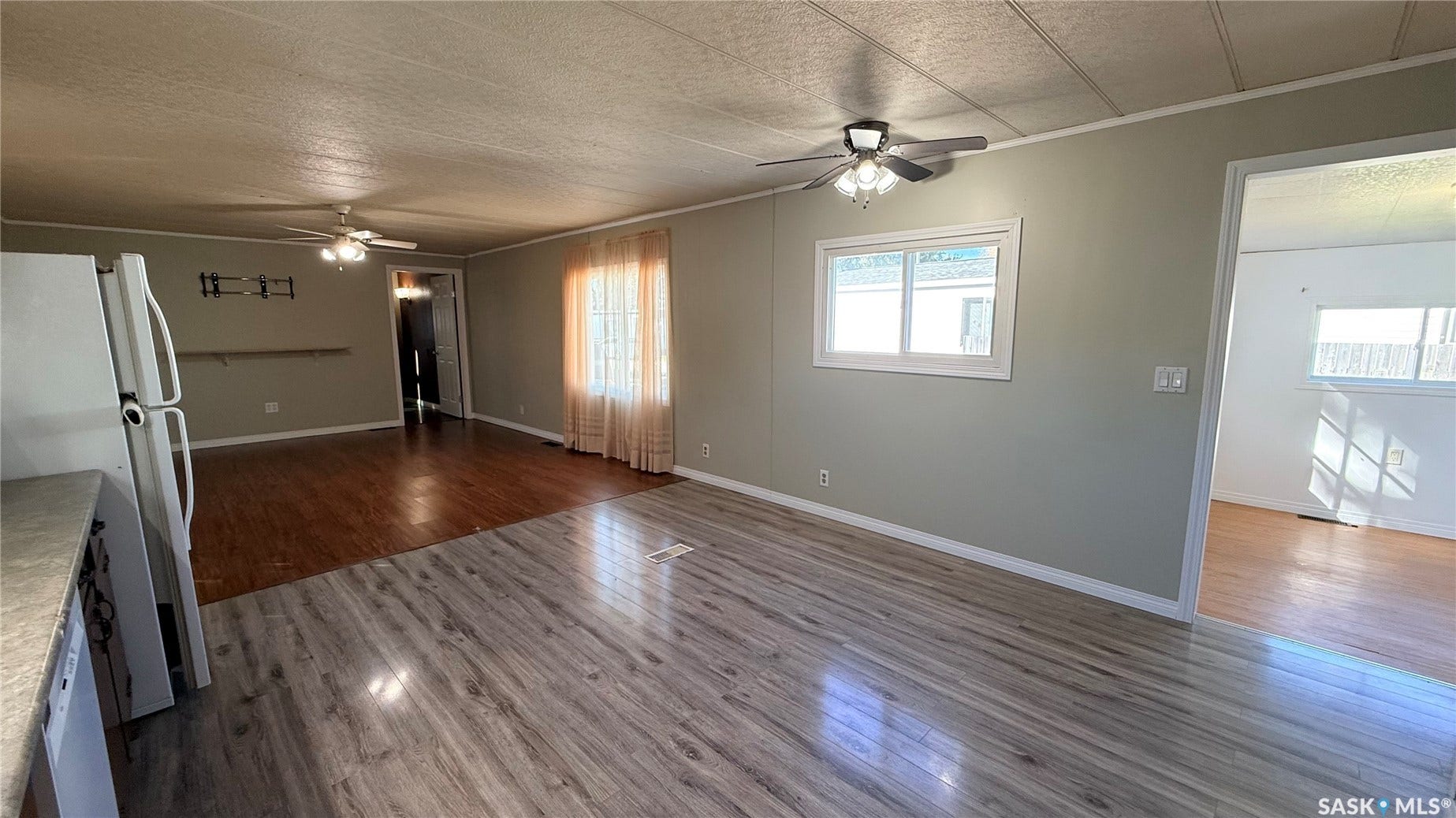 Wood-finish flooring, ceiling fan with light fixture, natural light from windows, and neutral wall paint
