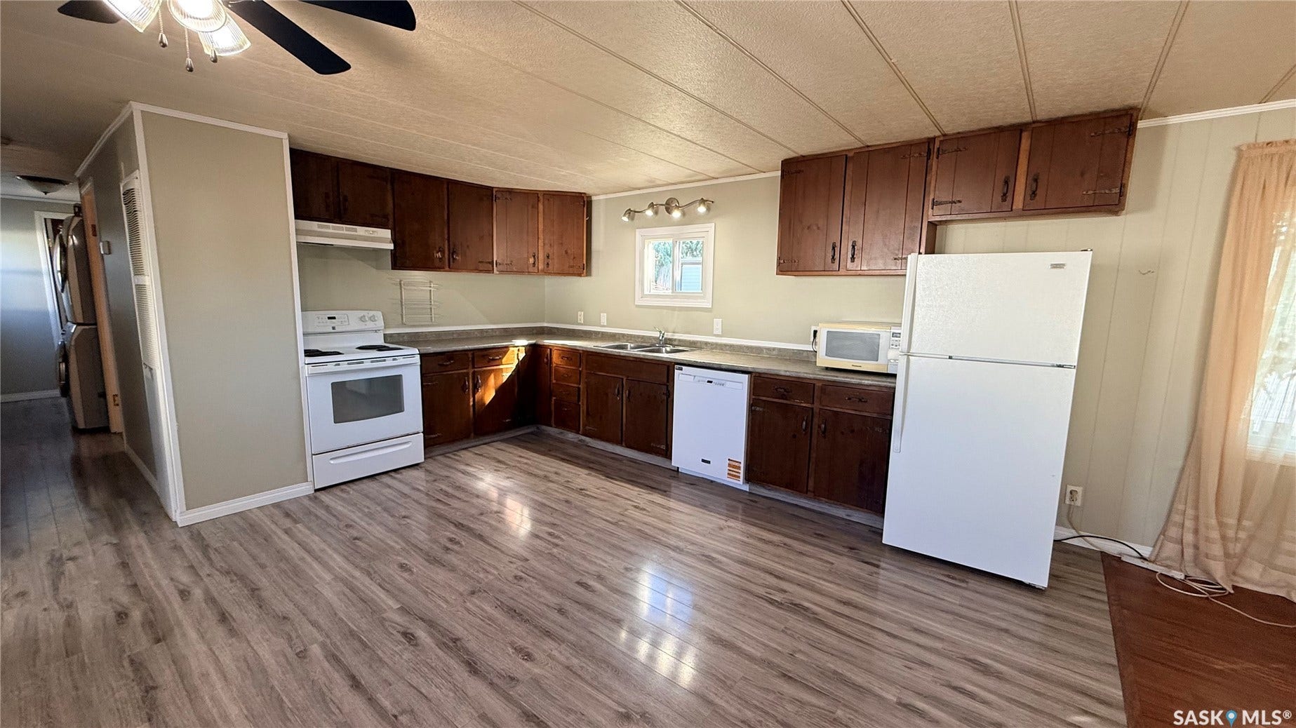Kitchen featuring wood-finish flooring, wood cabinetry, white appliances, and a double basin sink